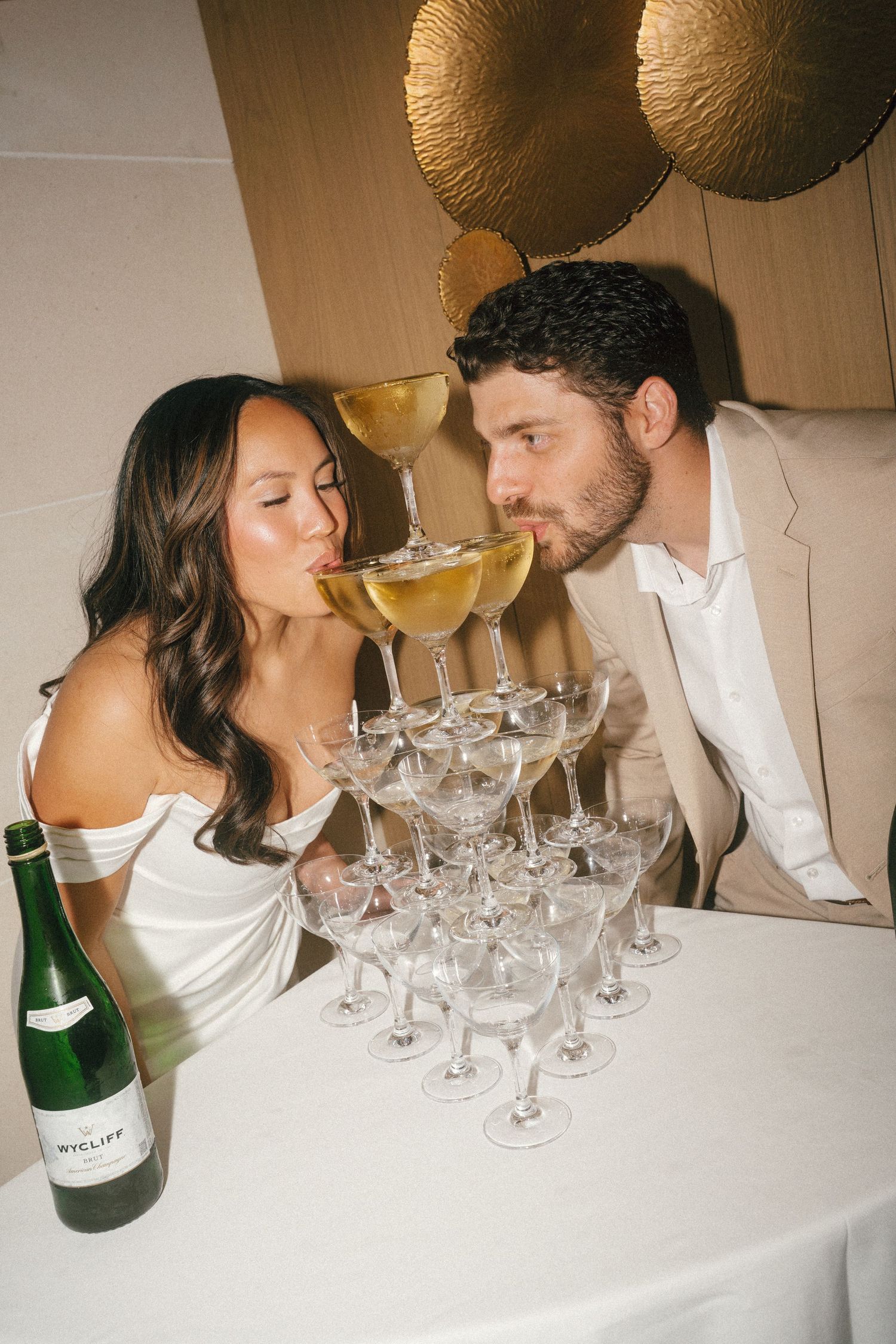 A champagne celebration with gold balloons and crystal glasses on a white tablecloth.