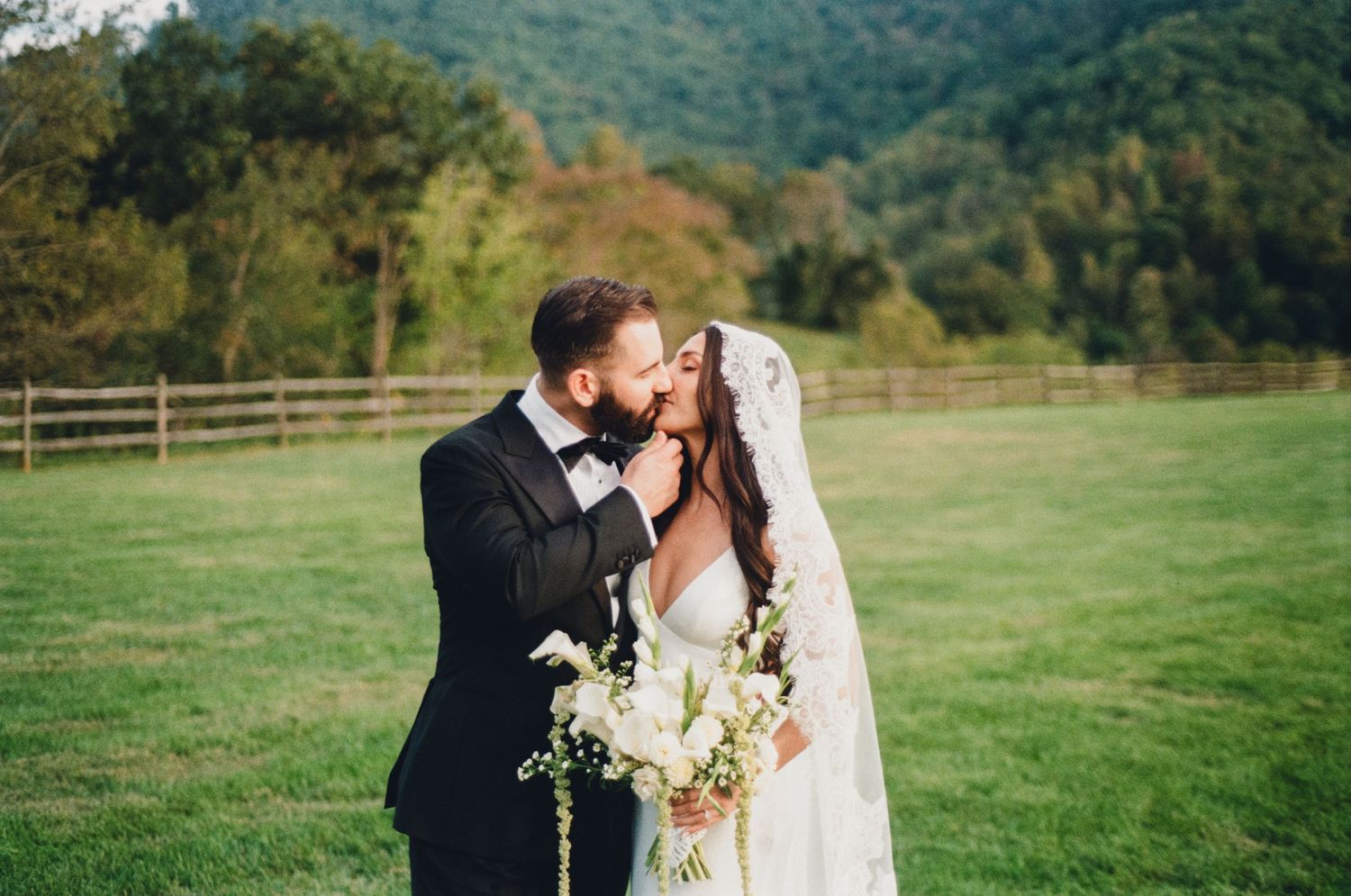 Romantic wedding moment captured against a backdrop of rolling green mountains.