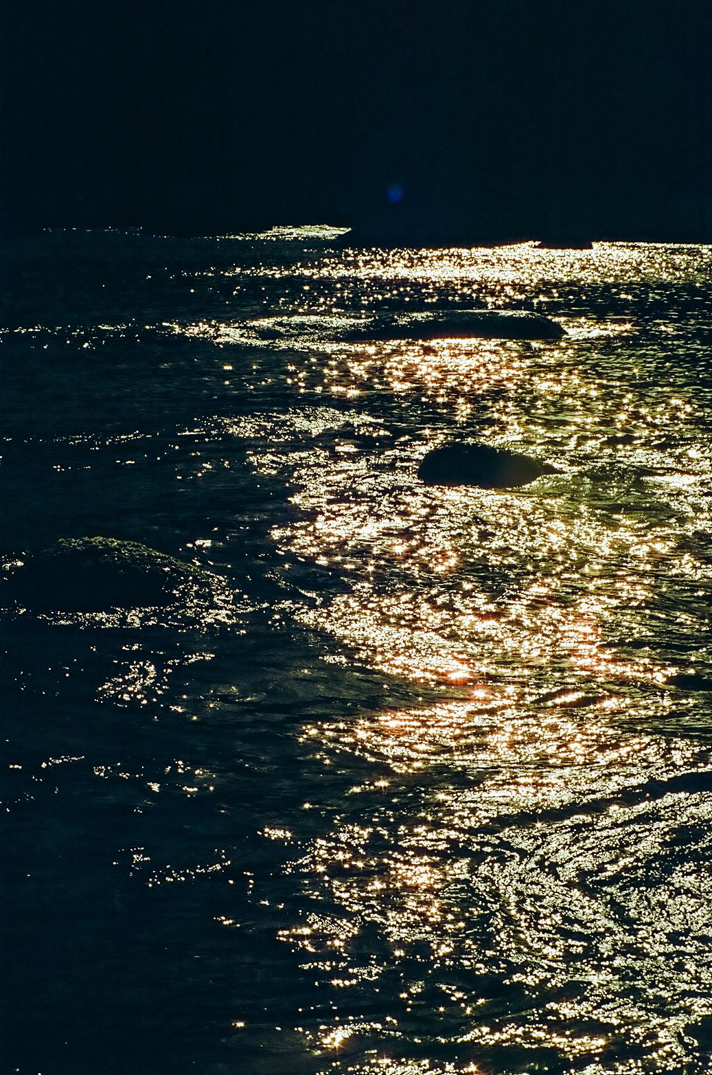 Sunlight reflecting off dark ocean waters creating sparkling patterns.