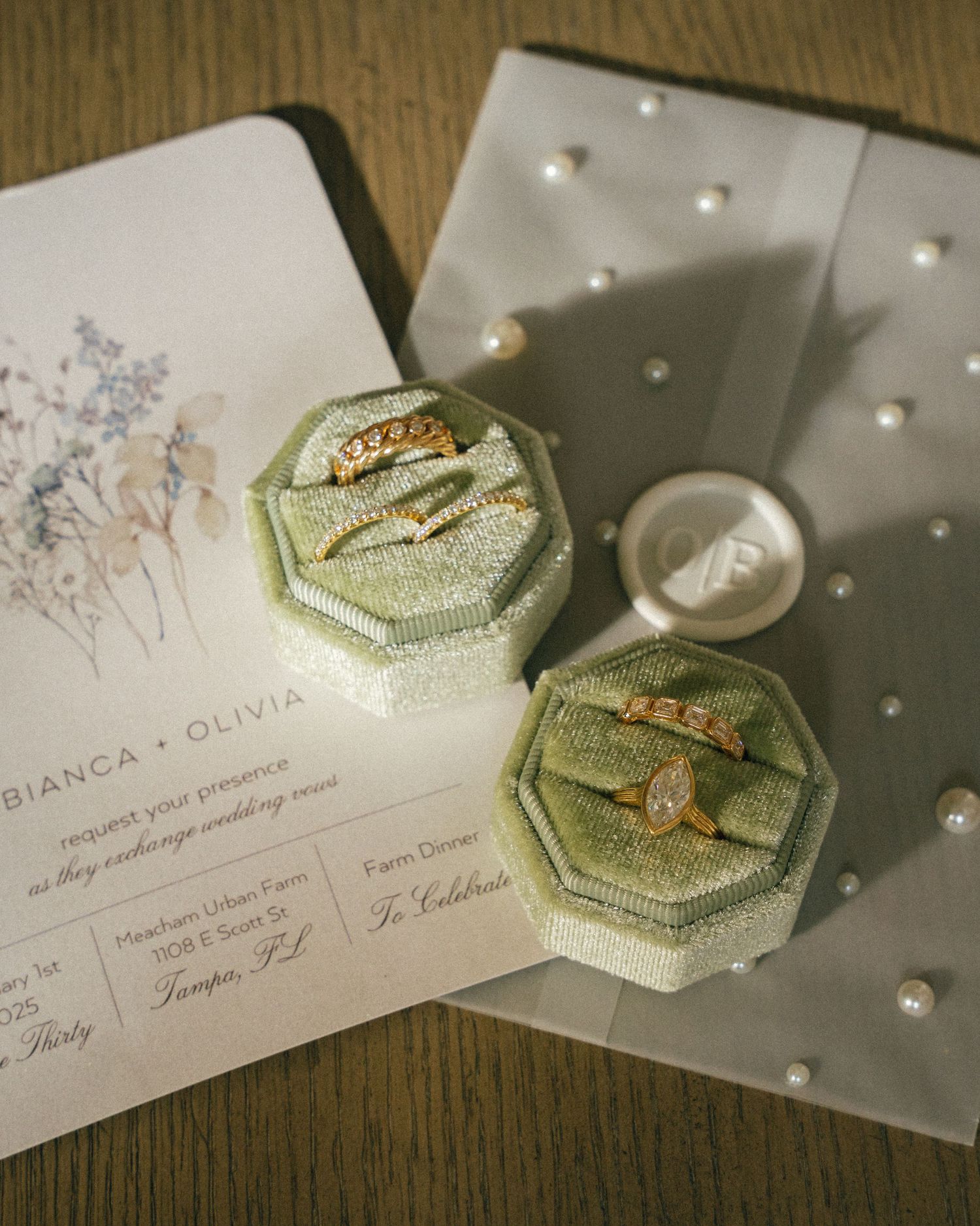 Wedding stationery featuring sage green embellishments and delicate pearls on wooden background.