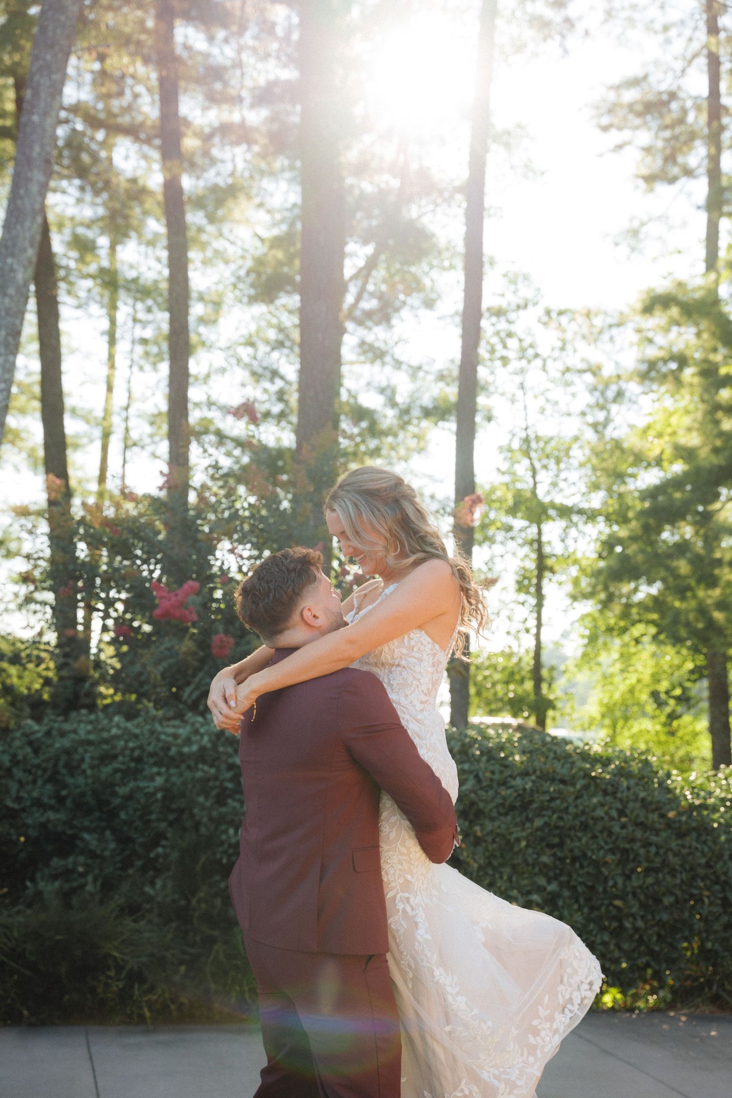 A couple performs an elegant dance move backlit by golden sunlight filtering through trees.