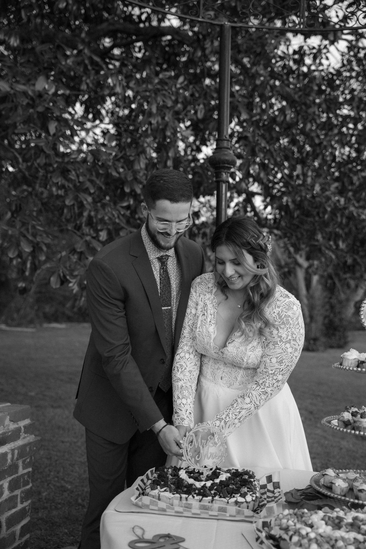 Couple cutting their wedding cake together at outdoor reception.