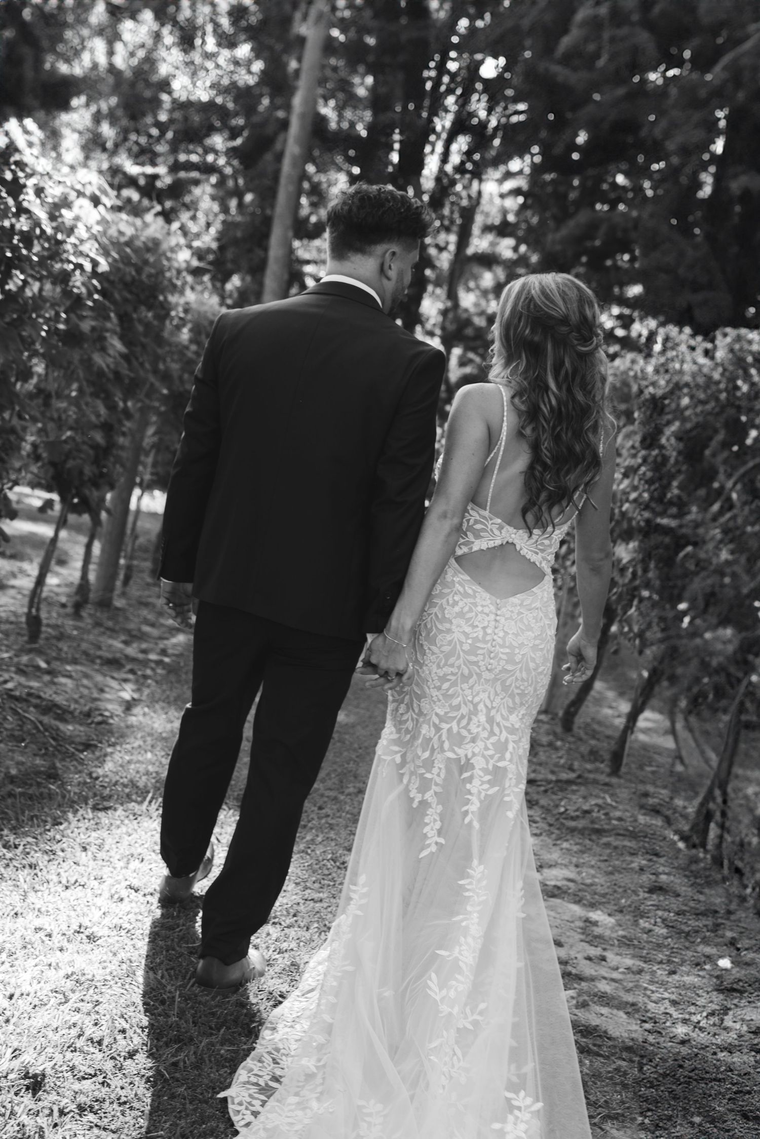 Black and white photo sequence of couple walking through wooded area in wedding attire.