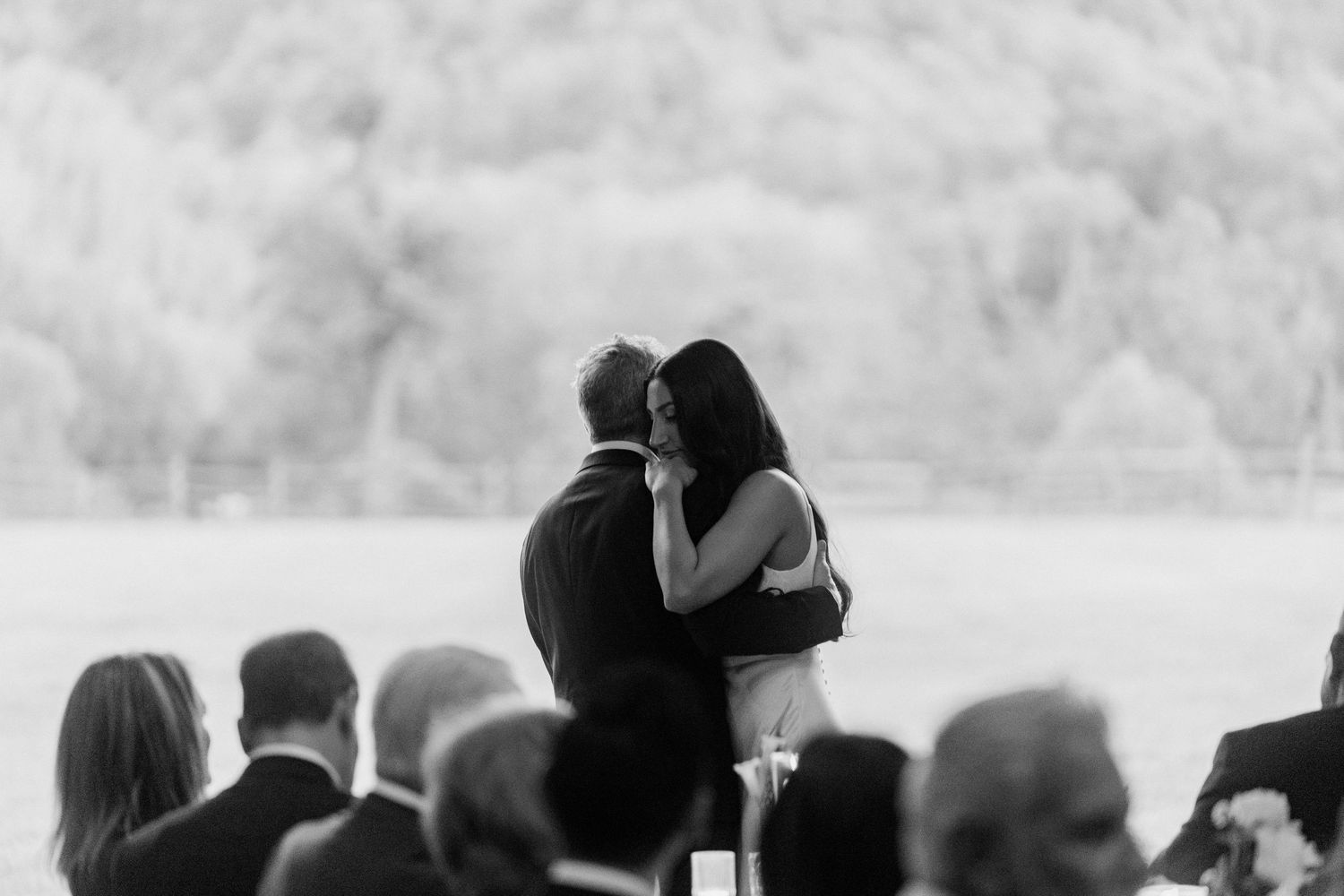 Black and white photo of a couple sharing their first kiss at an outdoor wedding ceremony.