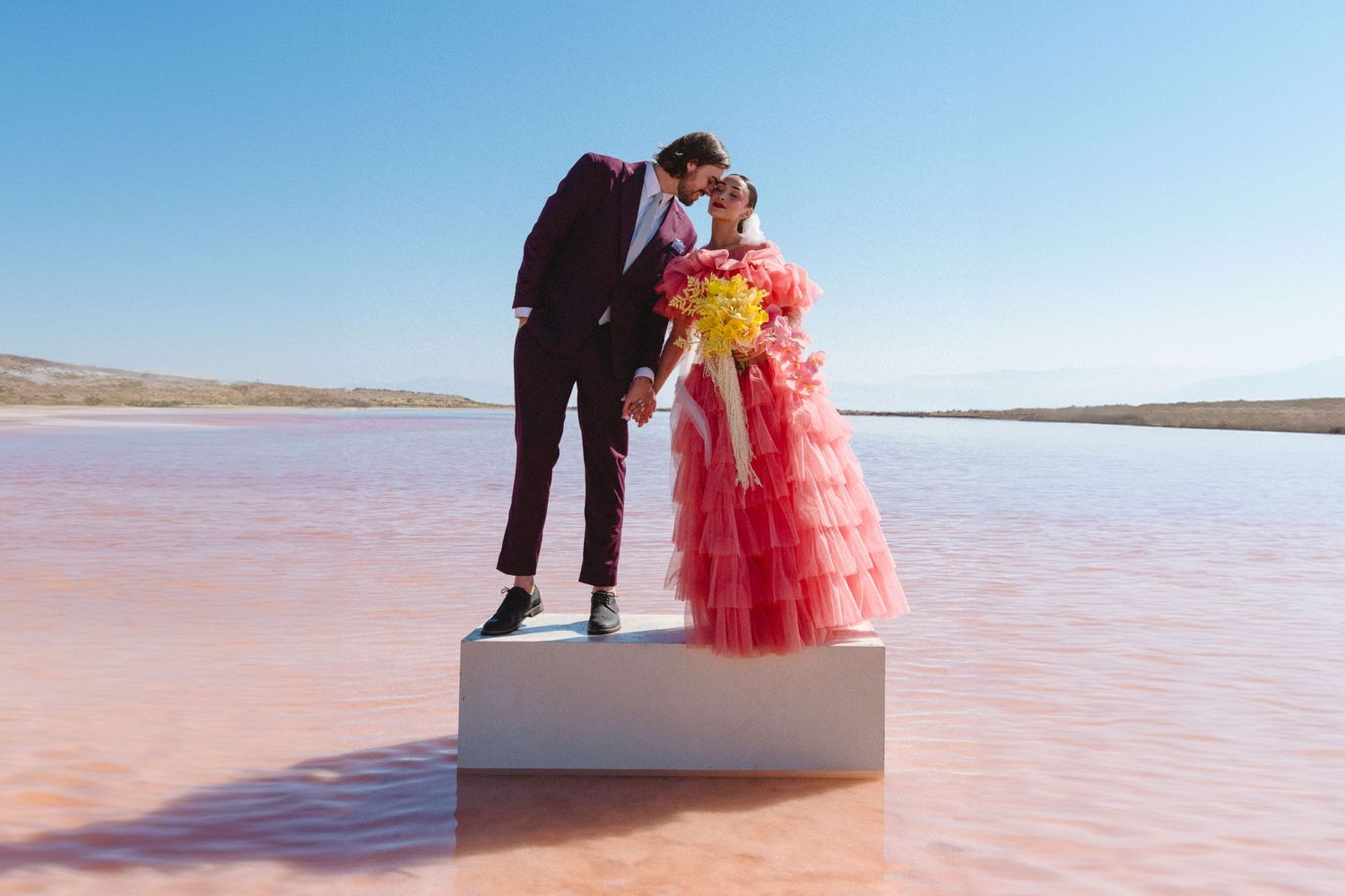 Artistic wedding photo sequence on pink salt flats with couple on white platform.