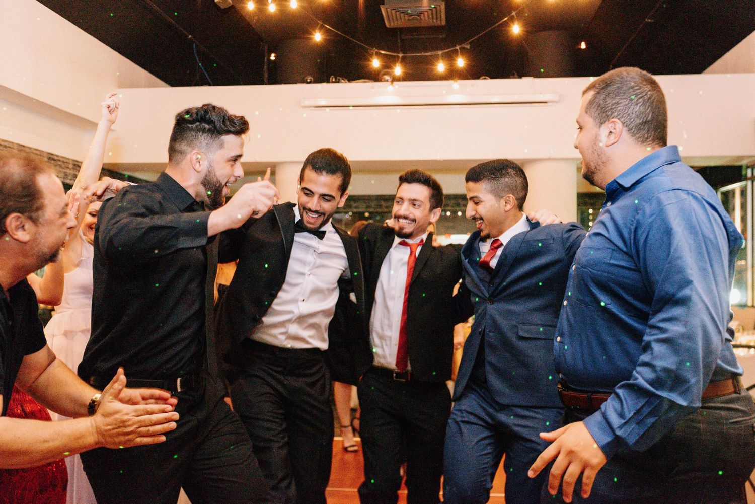 Groomsmen laughing and celebrating during a wedding reception.