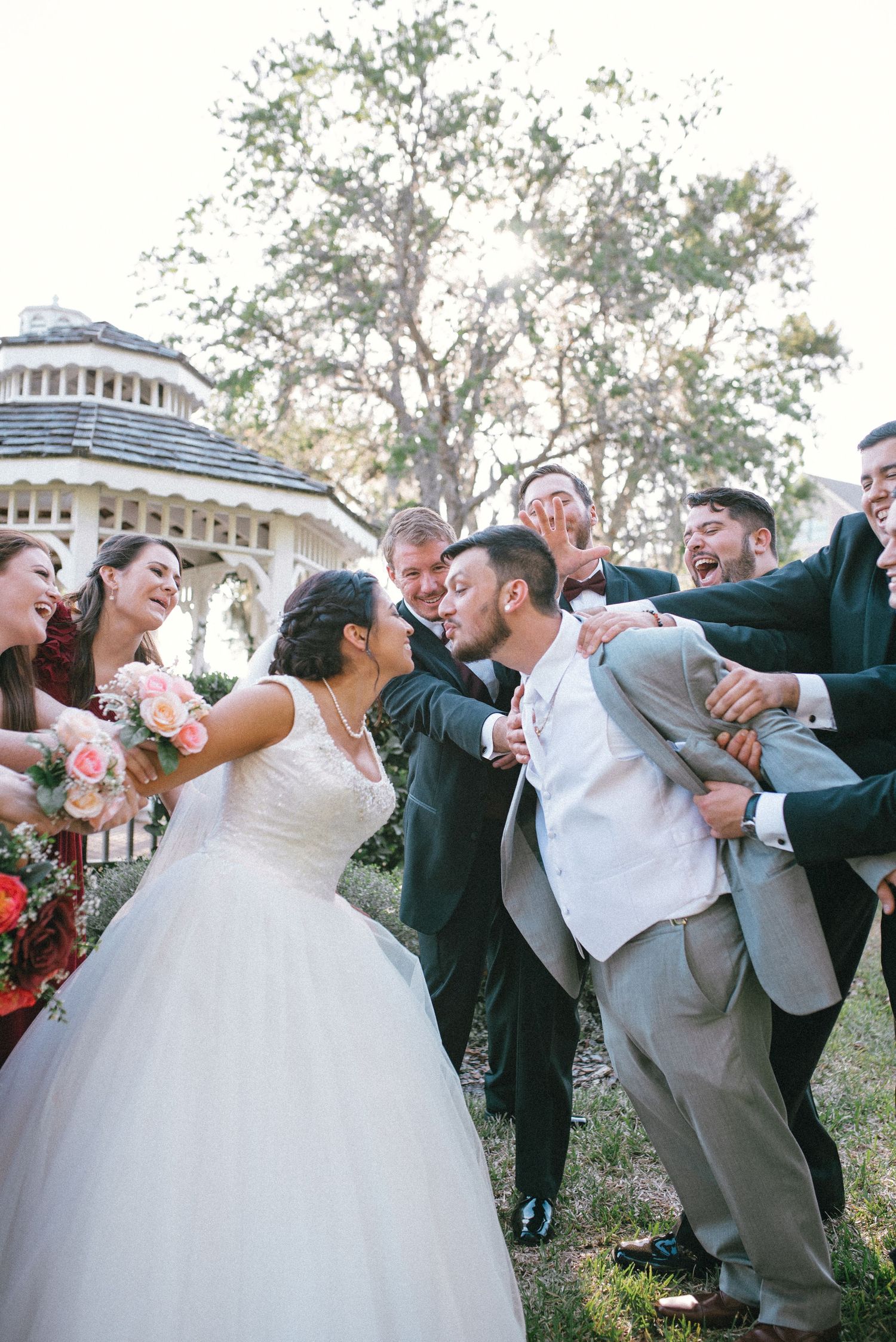 Wedding group creates energetic poses during outdoor photography session.