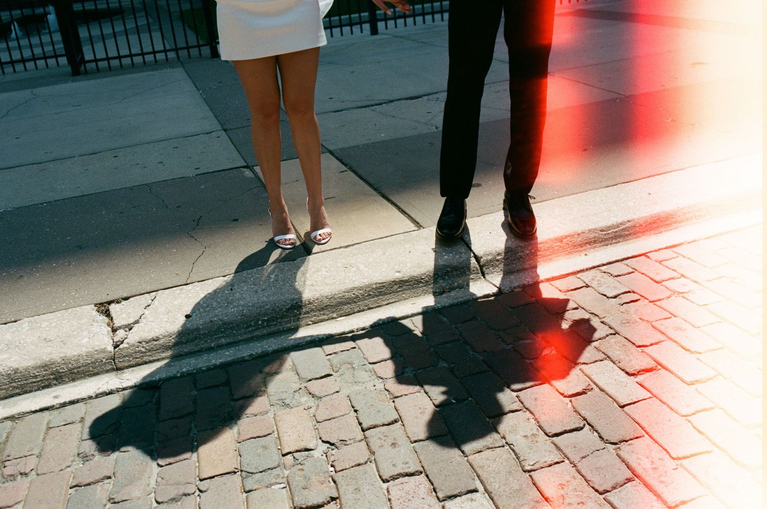 Wedding couple's shadows cast on brick pavement at sunset.