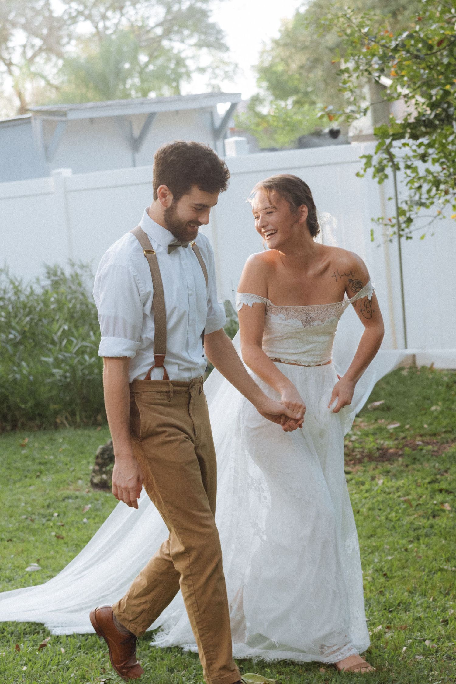 Casual wedding couple laughing together in a backyard garden setting.