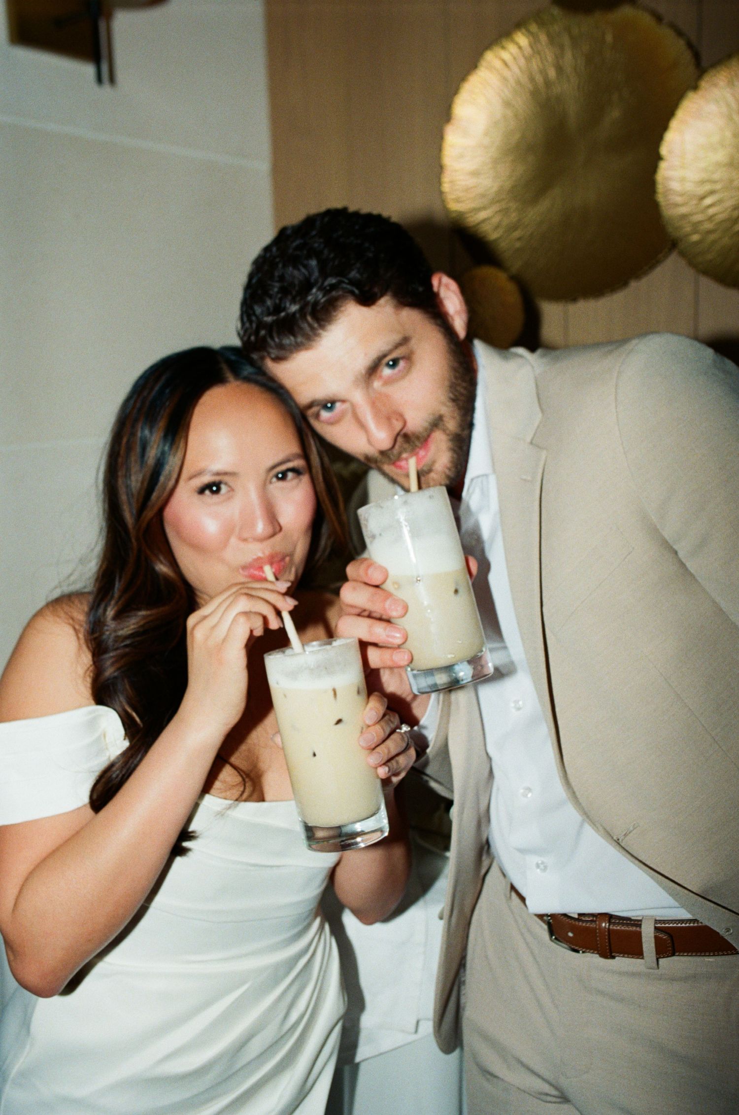 Couple sharing milkshakes together at indoor reception.