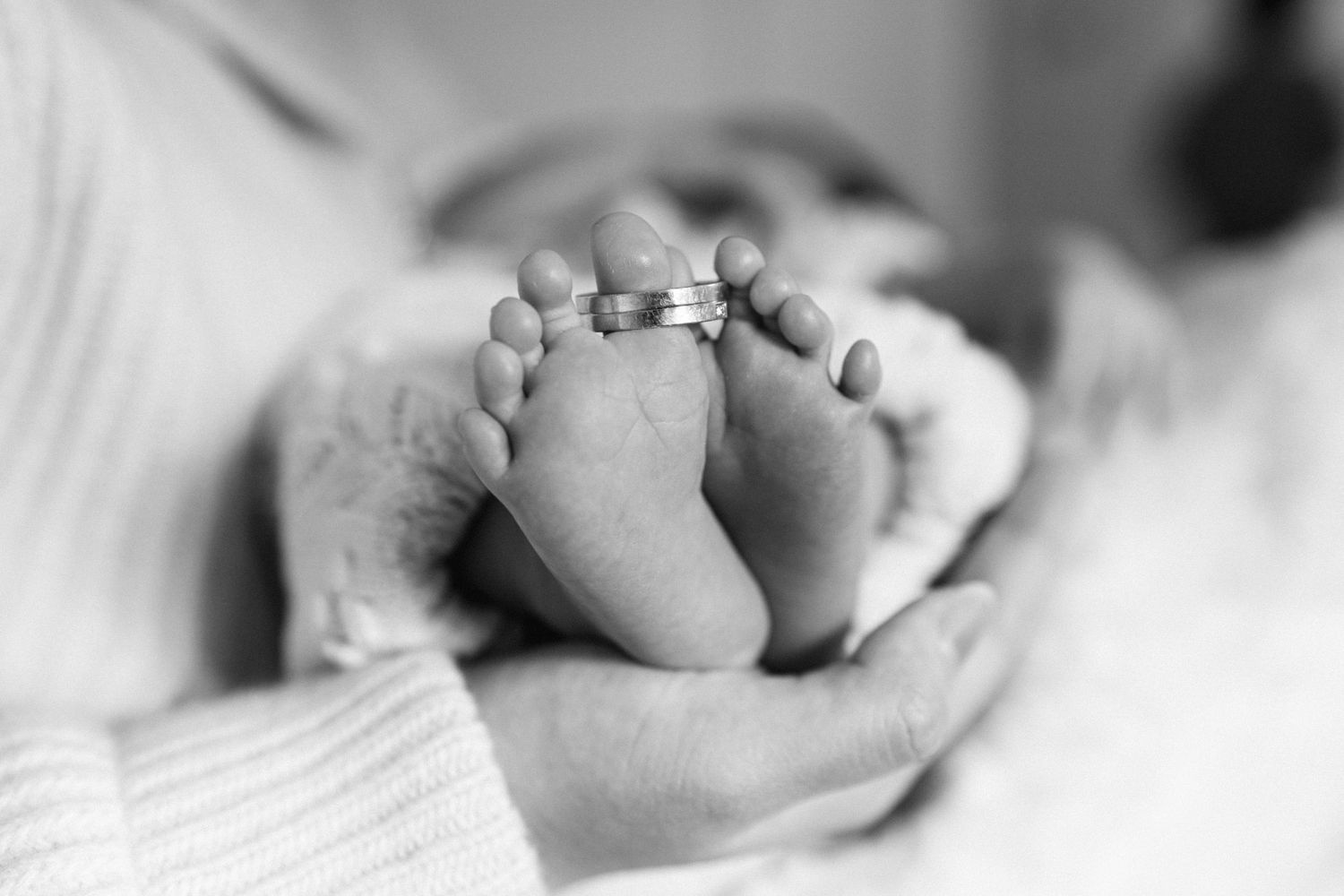 Newborn baby feet held gently in parent's hands — Boston family photographer Helen Fang Studio