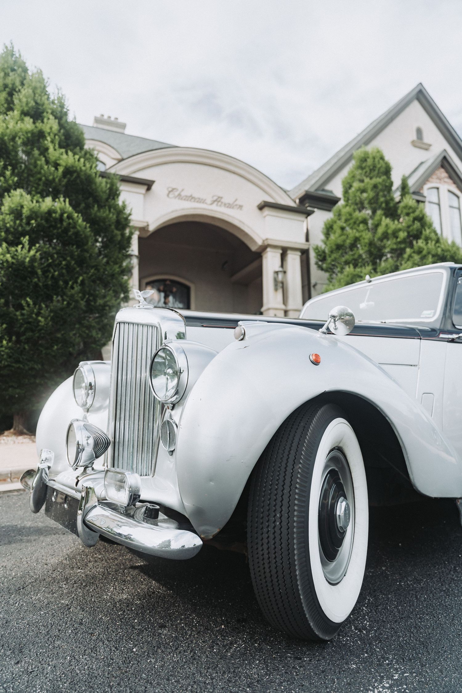 A classic white Rolls Royce vintage car parked outside an elegant wedding venue.