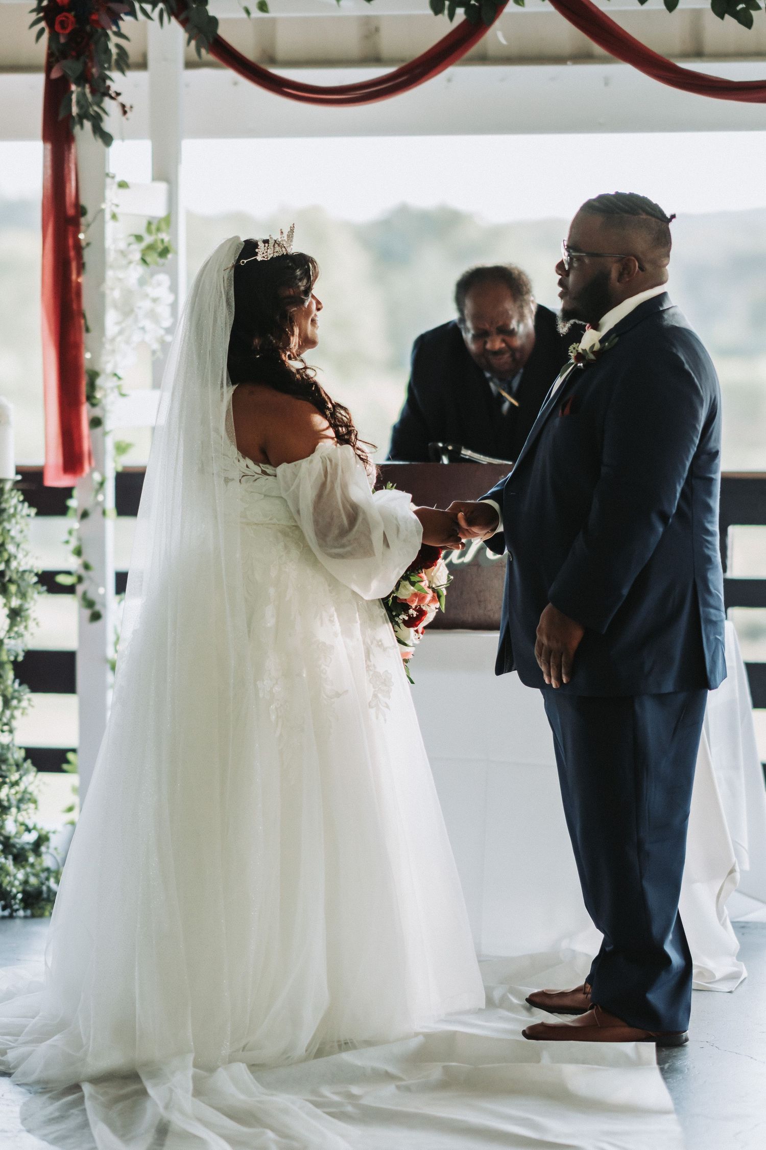 A couple exchanges vows under a decorated arch during their wedding ceremony.