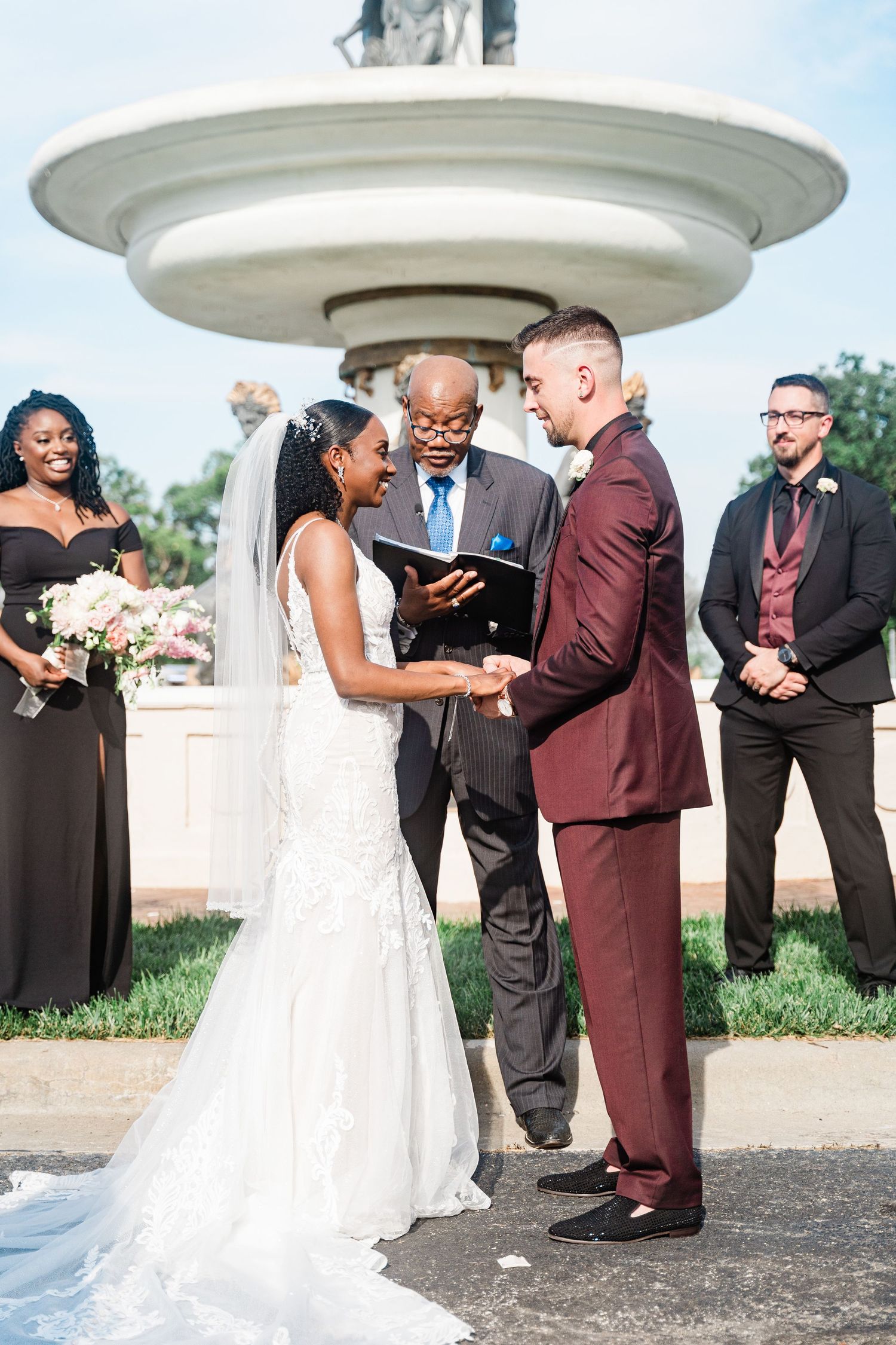 Outdoor wedding ceremony with couple exchanging vows under white gazebo with officiant.
