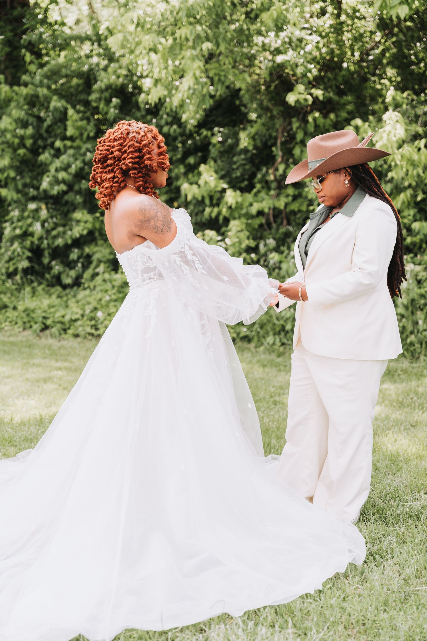 Two people in white attire sharing a joyous moment together during an outdoor wedding celebration.