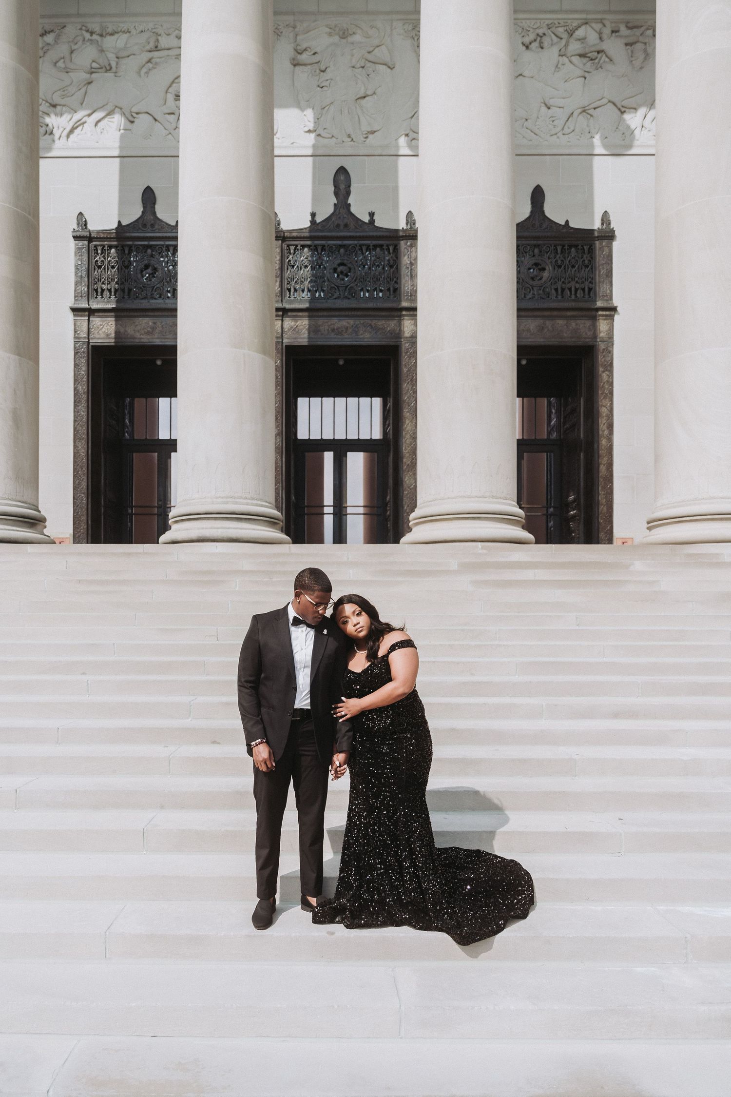 Formal couple portrait on grand white marble steps of classical building.
