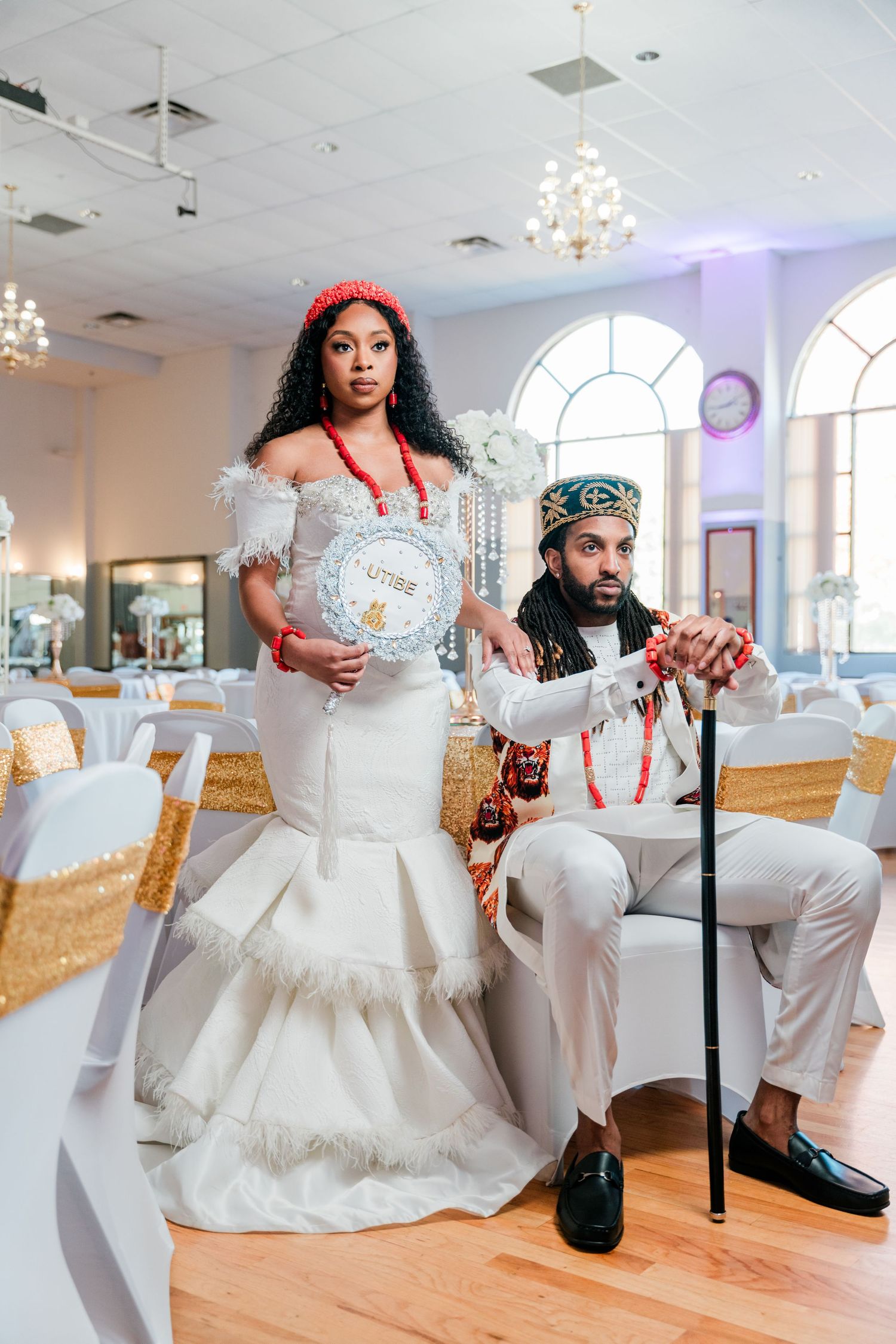 Wedding couple in modern attire featuring a white mermaid gown and traditional accessories.