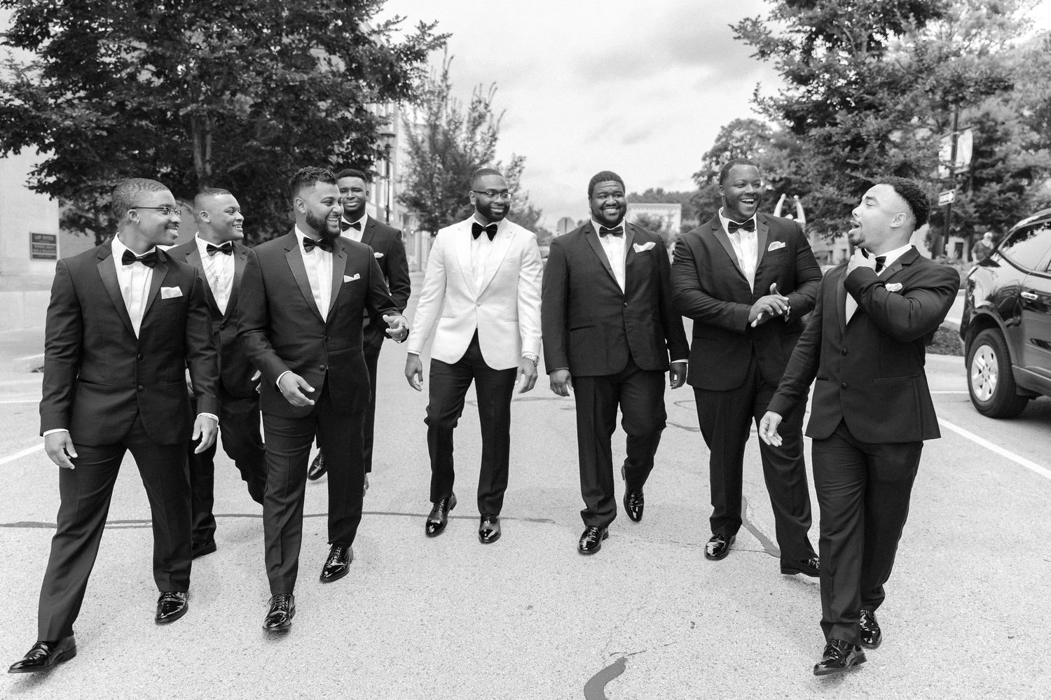 Black and white photo of groomsmen walking together in formal attire.