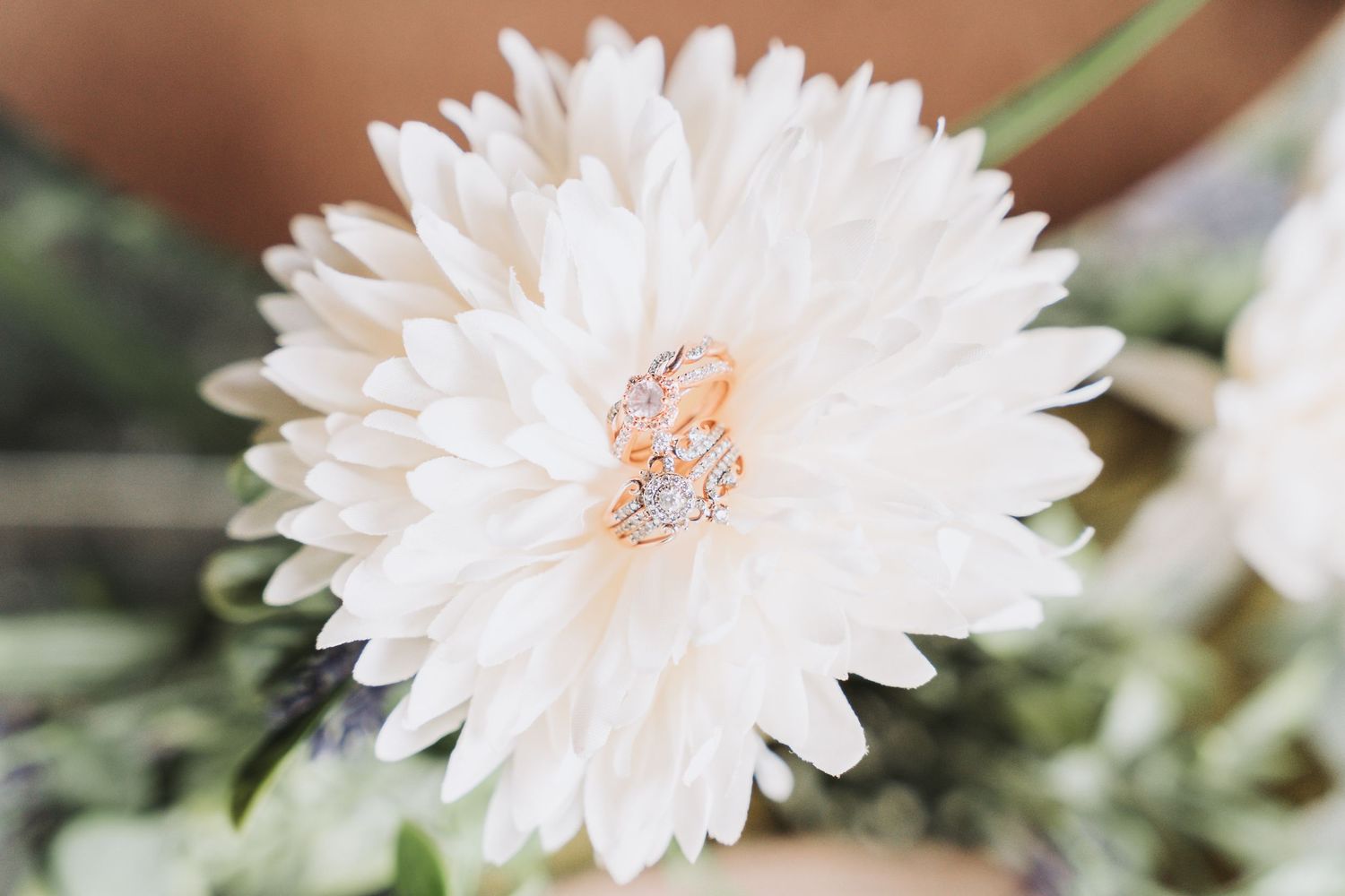 A delicate white flower displays wedding rings nestled in its petals.