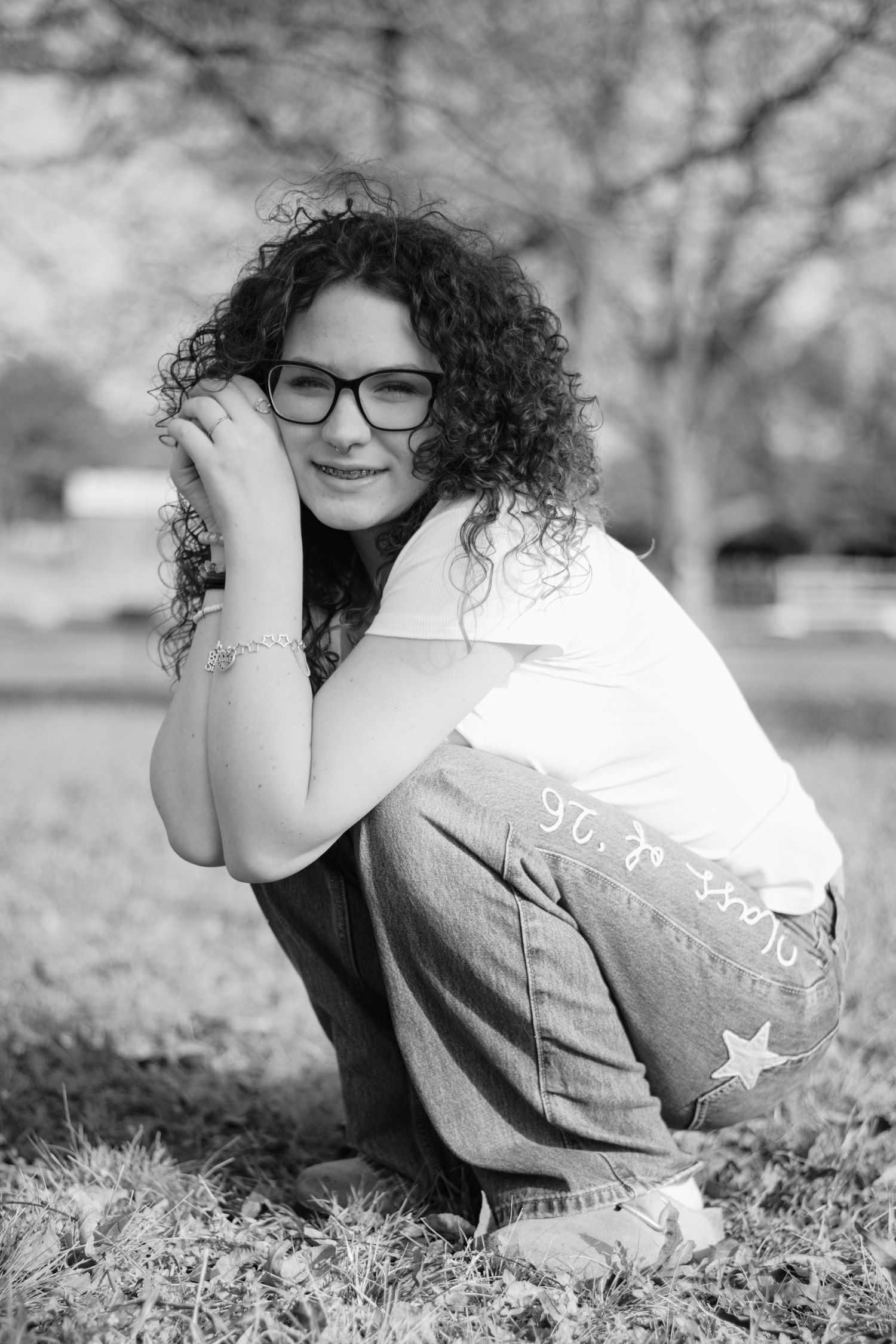 Black and white photos show a person with curly hair and glasses resting on grass in different relaxed poses.