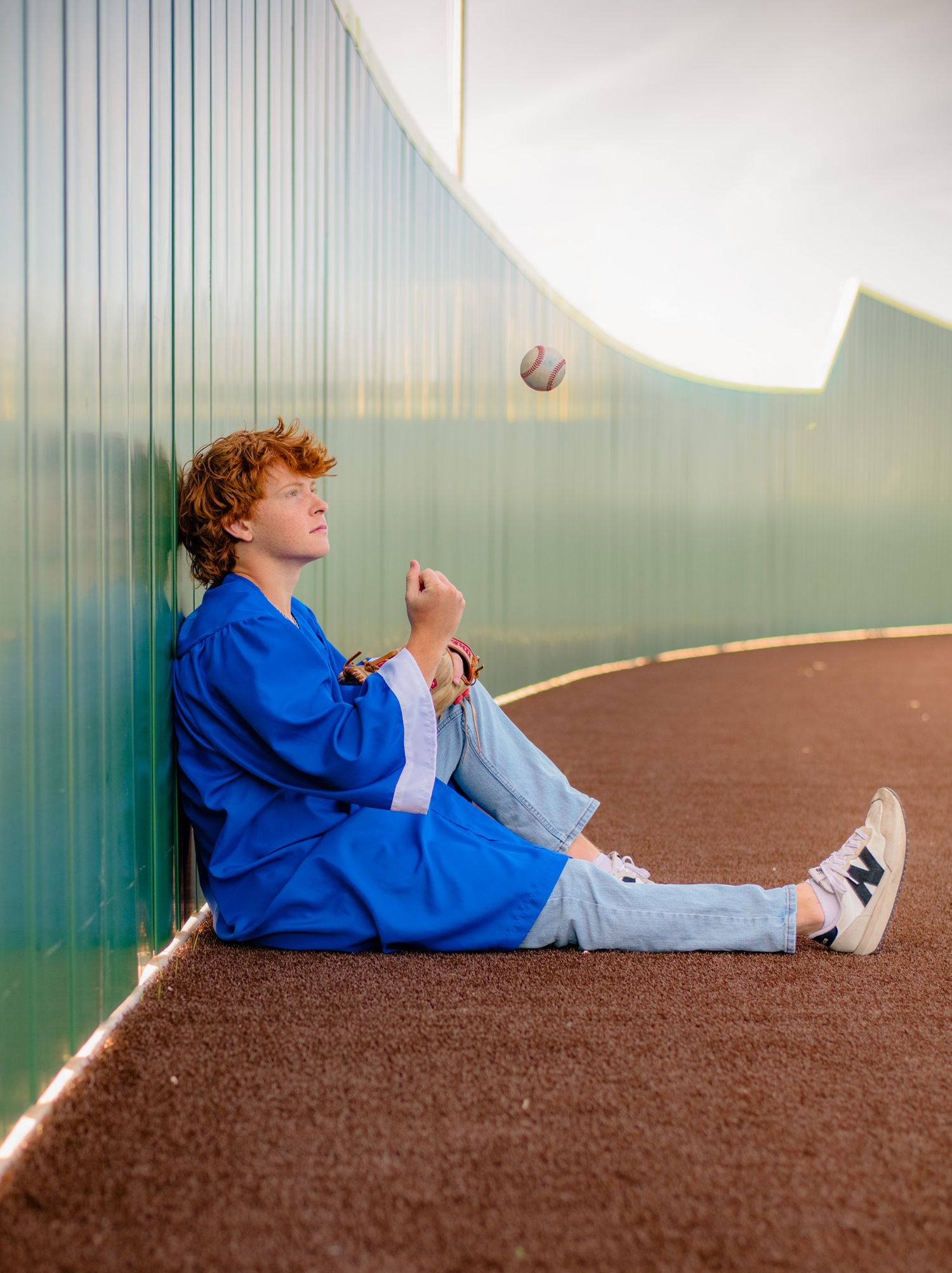 A person in a blue jacket lies on a brown surface while performing a sequence of rolling movements.