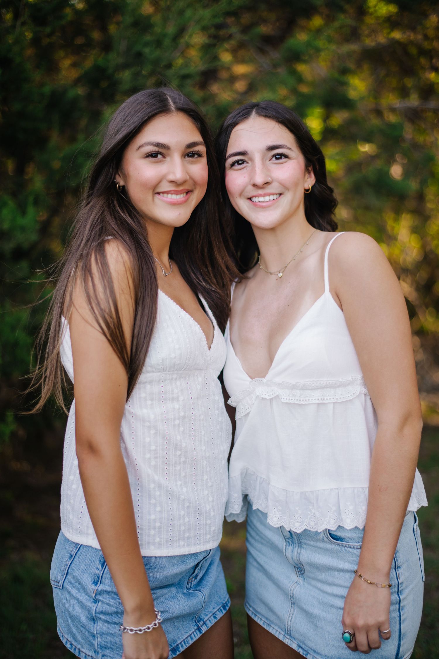 Two friends wearing white tops and denim sit together outdoors in a series of candid portrait photos.