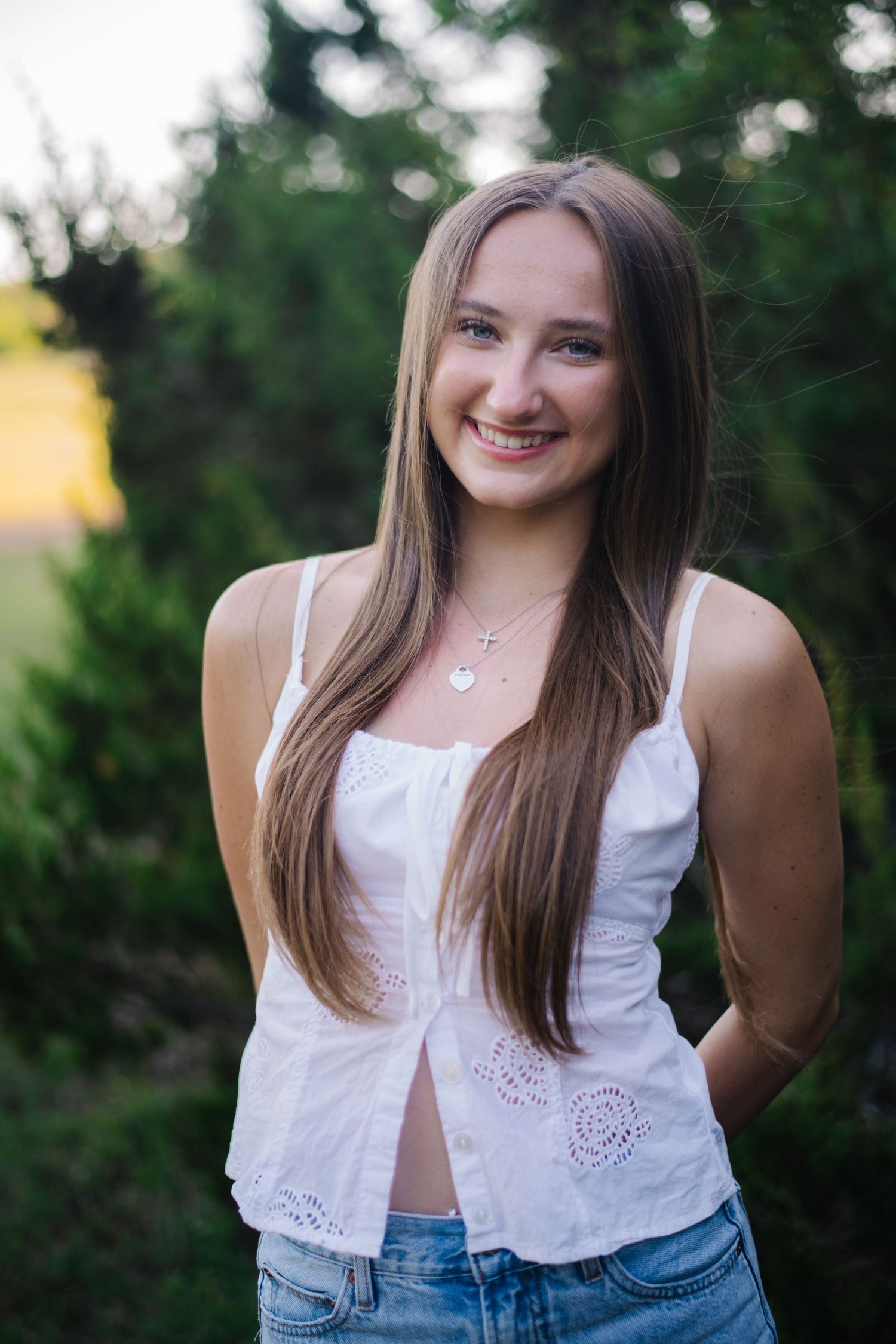 A person in a white lace crop top and denim poses outdoors in a series of casual summer portraits.