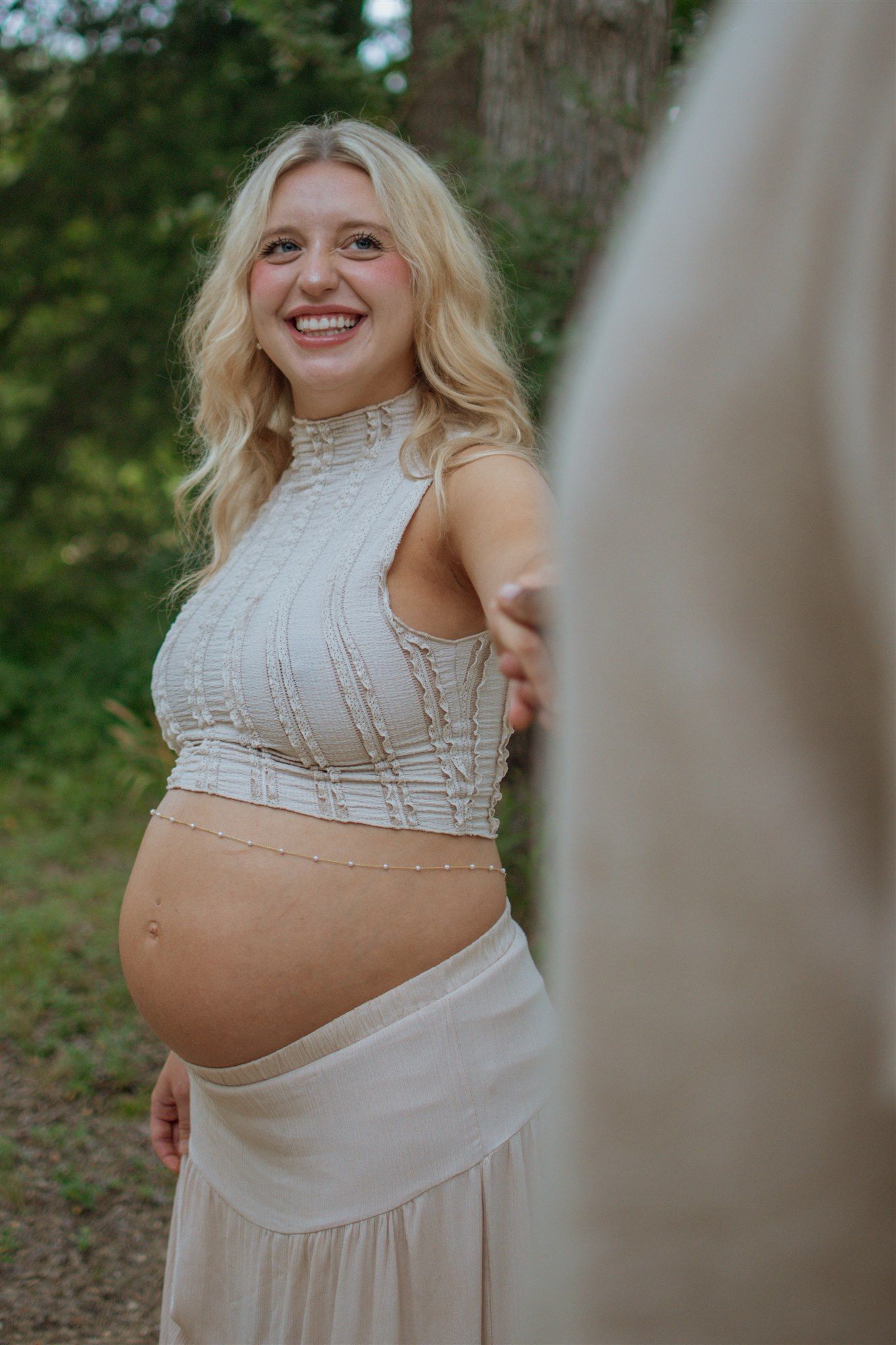 A series of maternity photos showing a pregnant woman in a white lace top against a natural outdoor background.