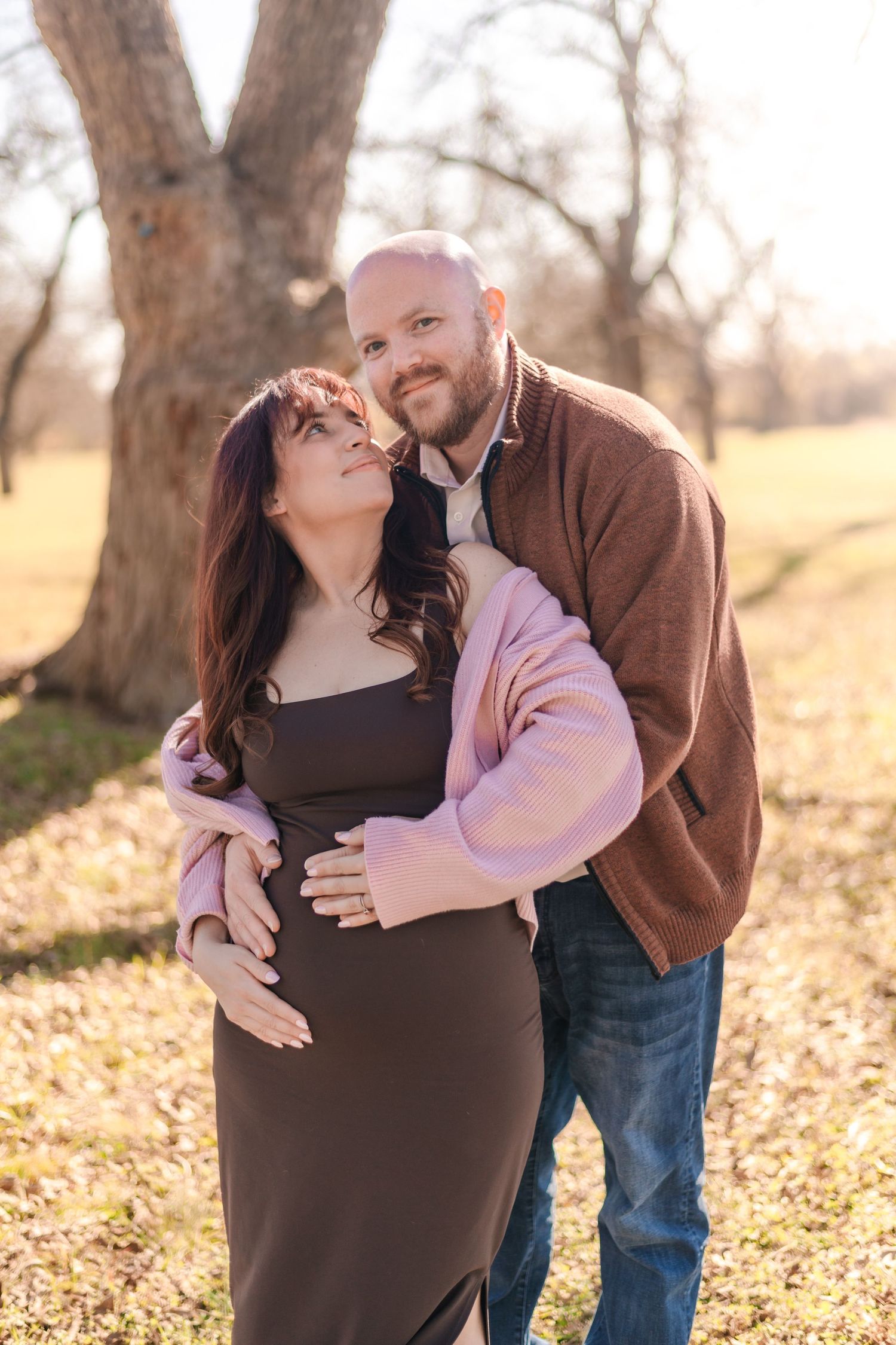 A couple embraces in a romantic autumn photoshoot with fallen leaves on the ground at sunset.