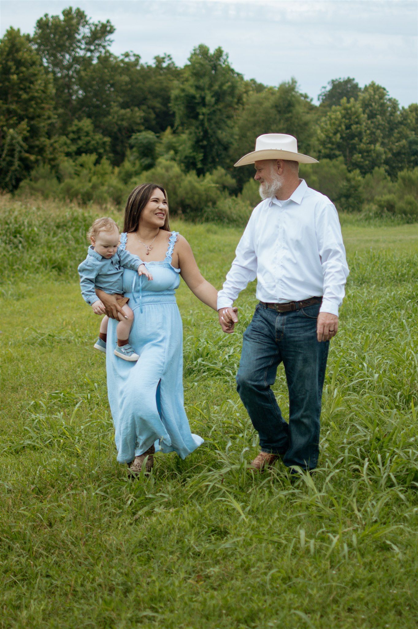 Family walking together through a green summer meadow on a sunny afternoon.