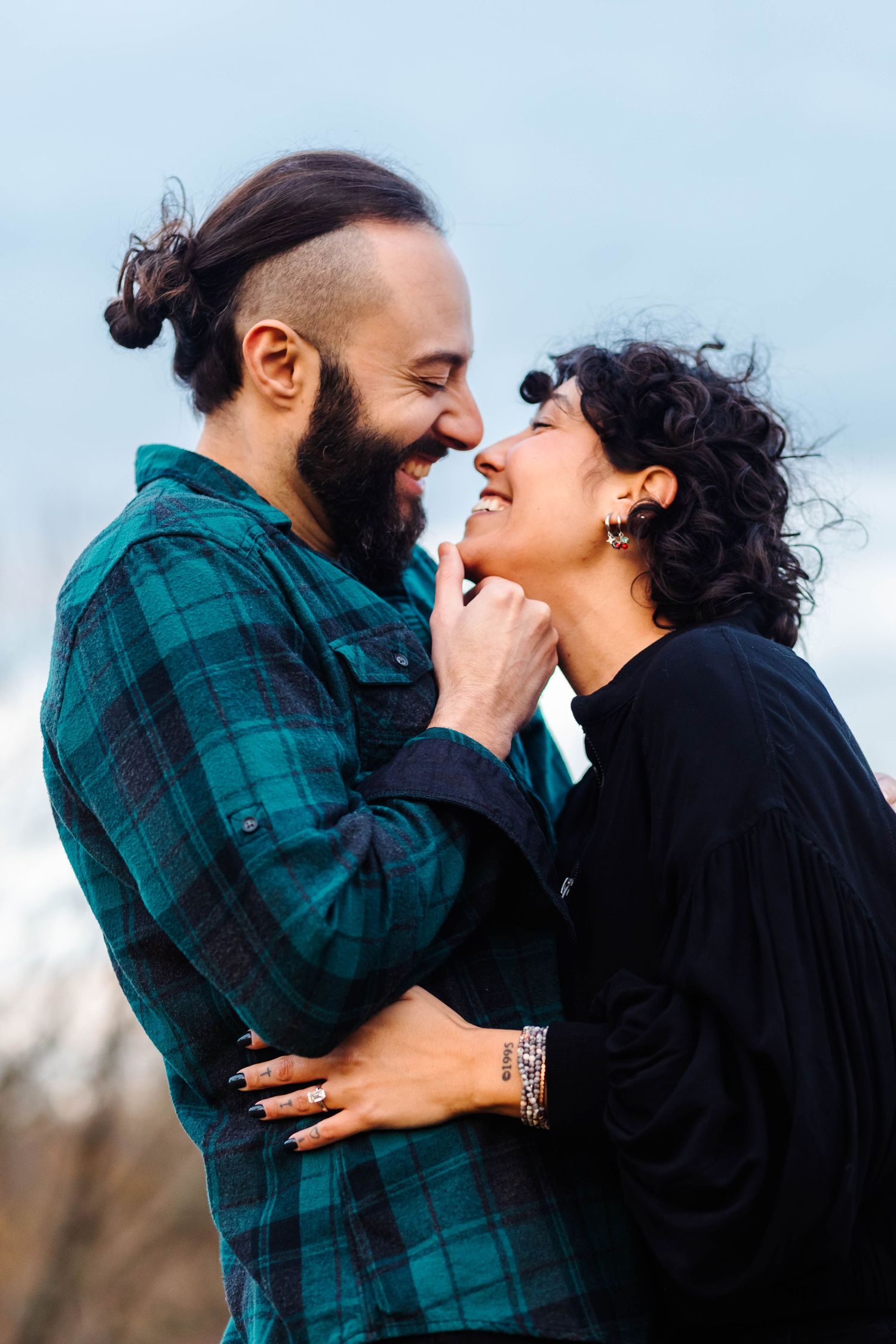 Bearded man with hair bun and curly-haired woman laughing together during fall engagement session in West Chester, PA.