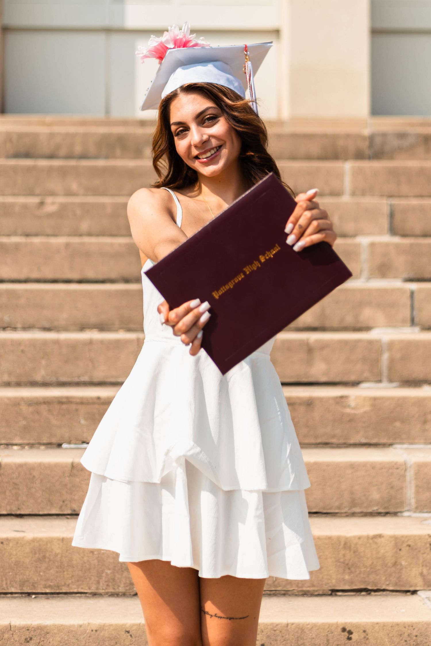 Pottstown Senior Session in white dress and cap proudly displaying her high school diploma on outdoor stone steps.