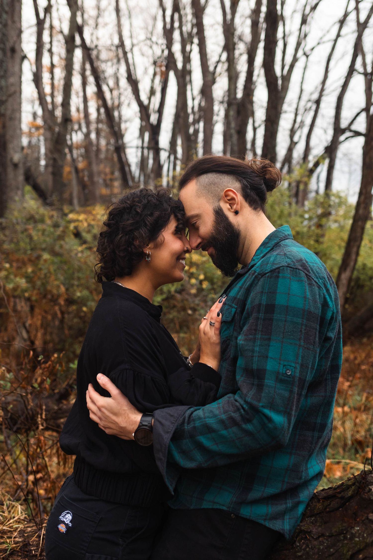 Couple embracing forehead to forehead in a wooded autumn forest during engagement photos in West Chester, PA.