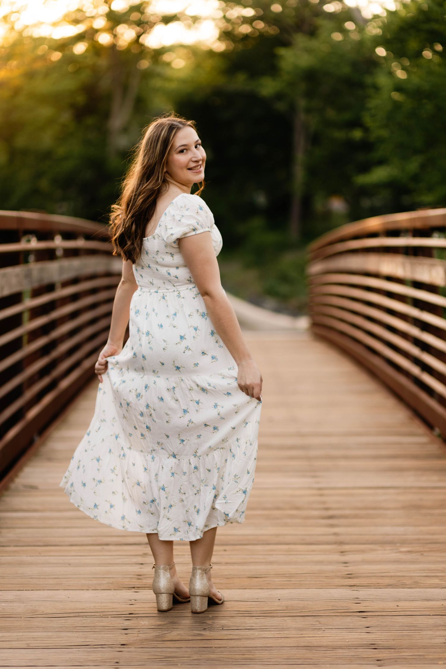 Boyertown Senior Session in floral white dress twirls on wooden bridge at golden sunset at Harleysville, PA.