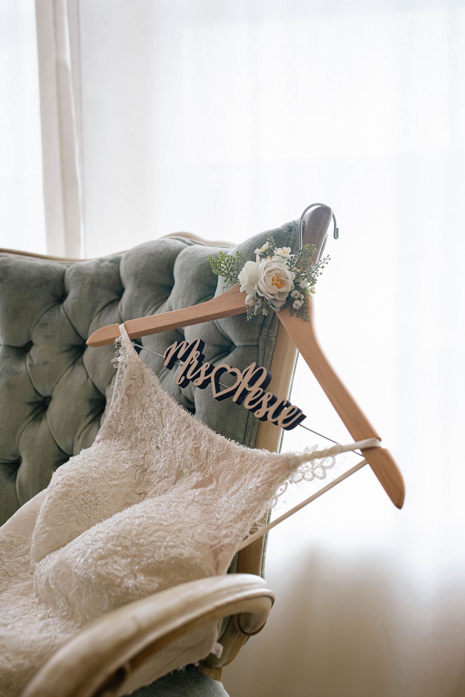 Detail shot of a wedding dress draped on a tufted velvet chair.