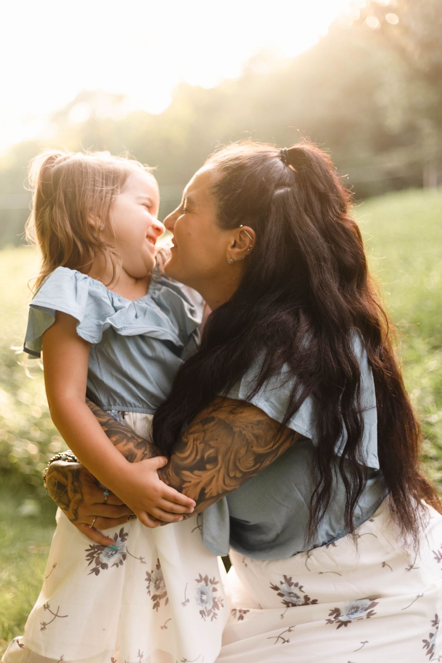 Mother and young daughter share joyful nose-to-nose moment in sun-drenched outdoor family portrait session in Boyertown, PA.
