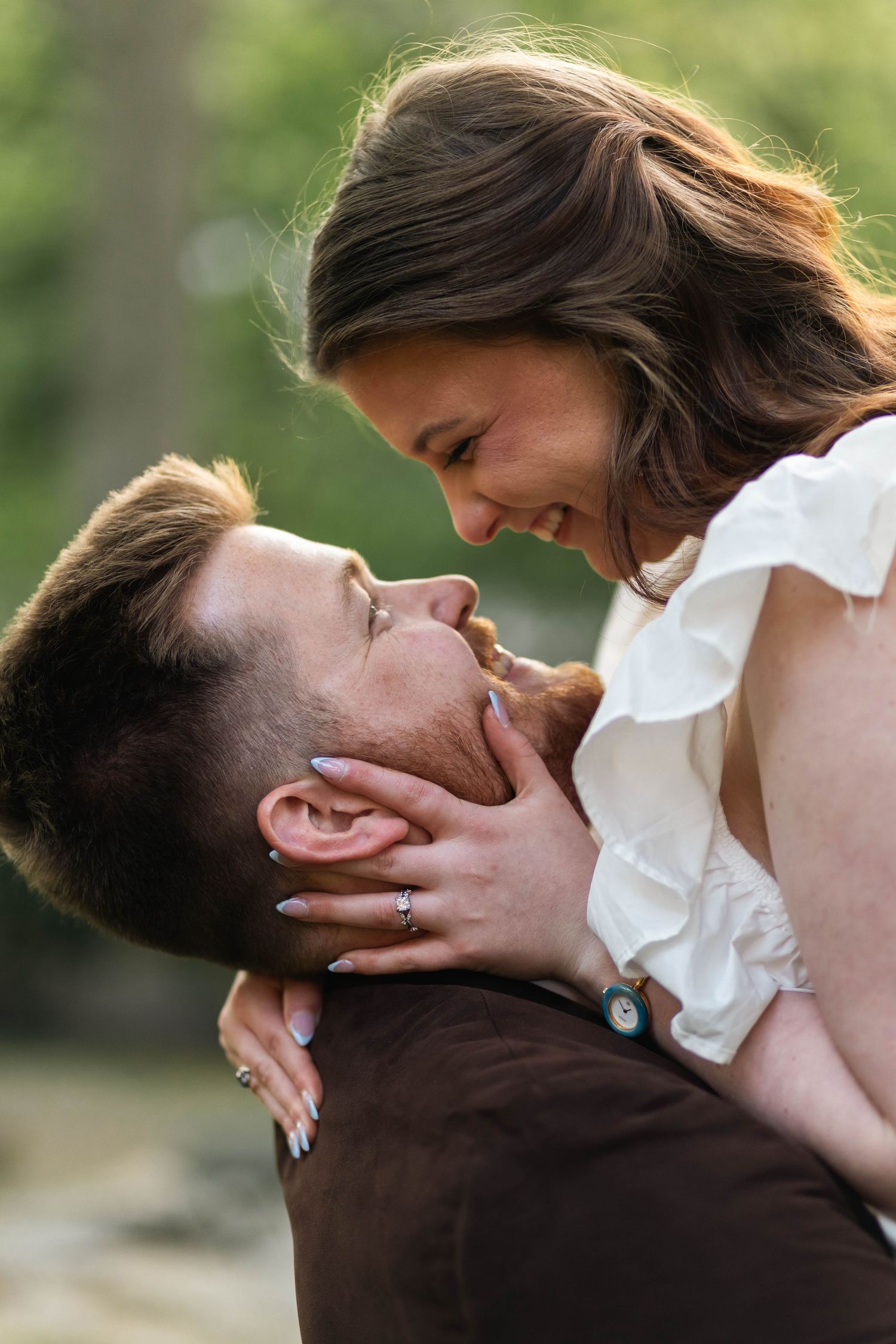Man lifting woman outdoors as they laugh and gaze lovingly at each other in nature in West Chester, PA.