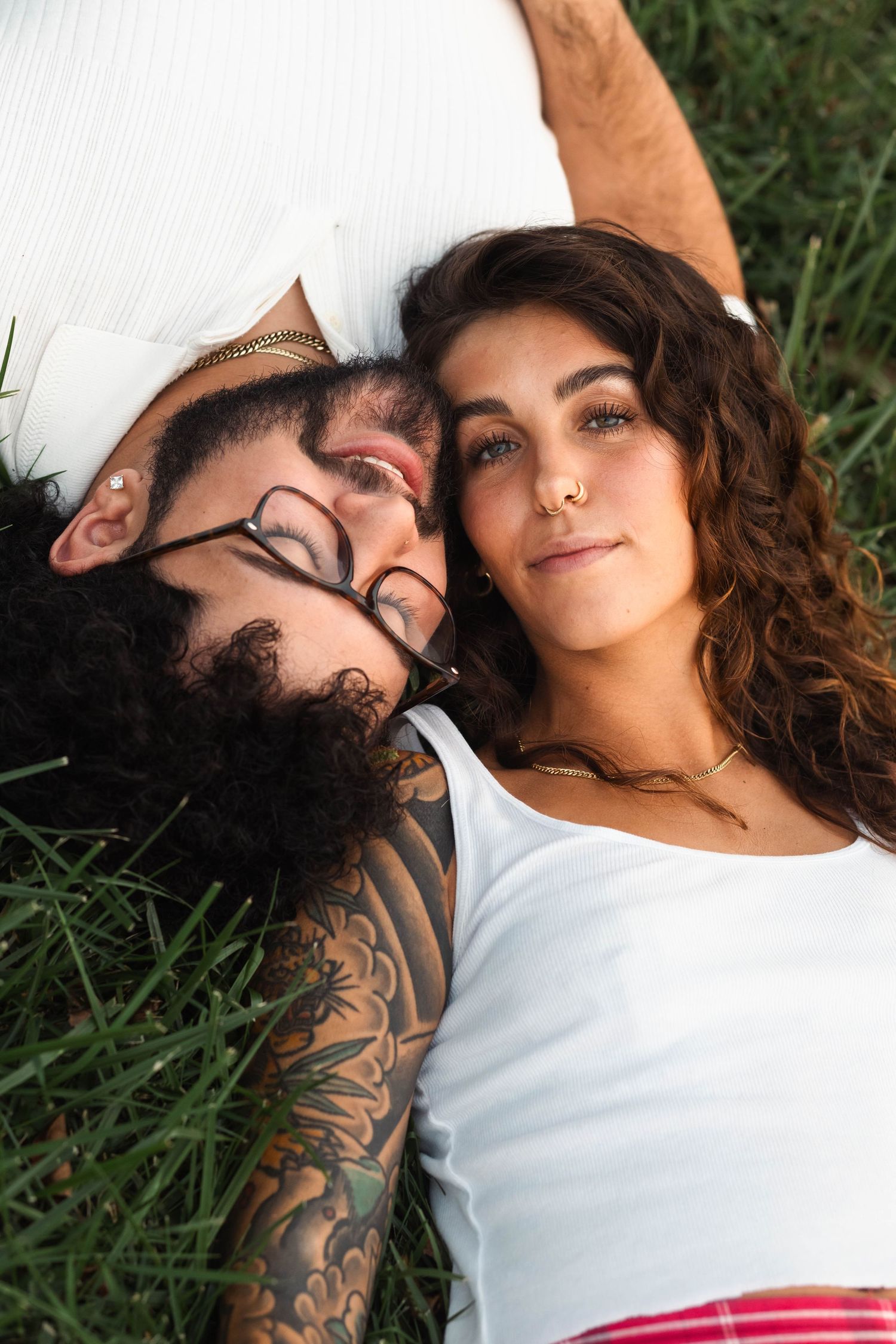 Couple lying in green grass together during an engagement session in Elverson, PA.