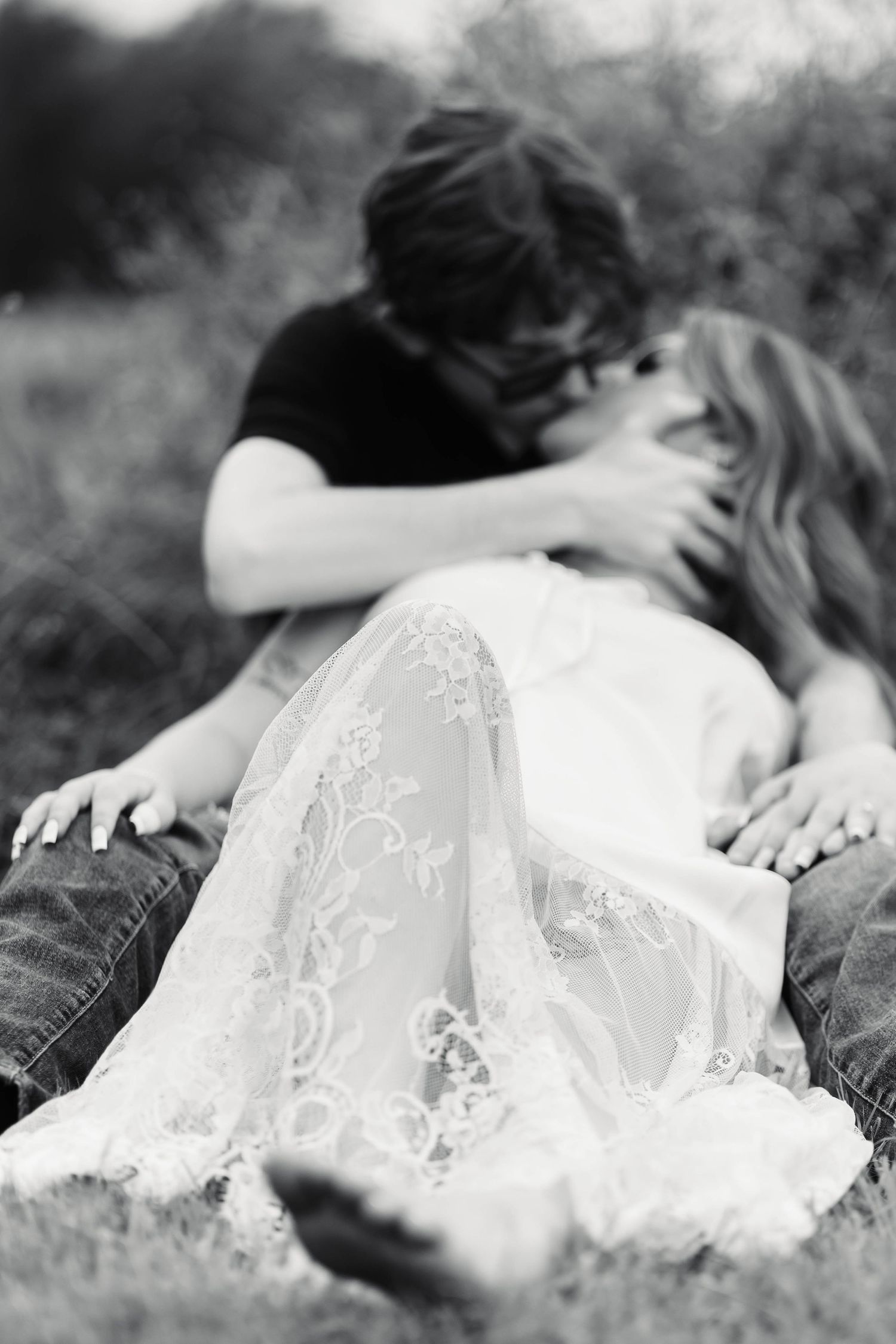 A black and white romantic photo of a couple kissing in a grassy outdoor setting during an engagement session in Oley, PA.