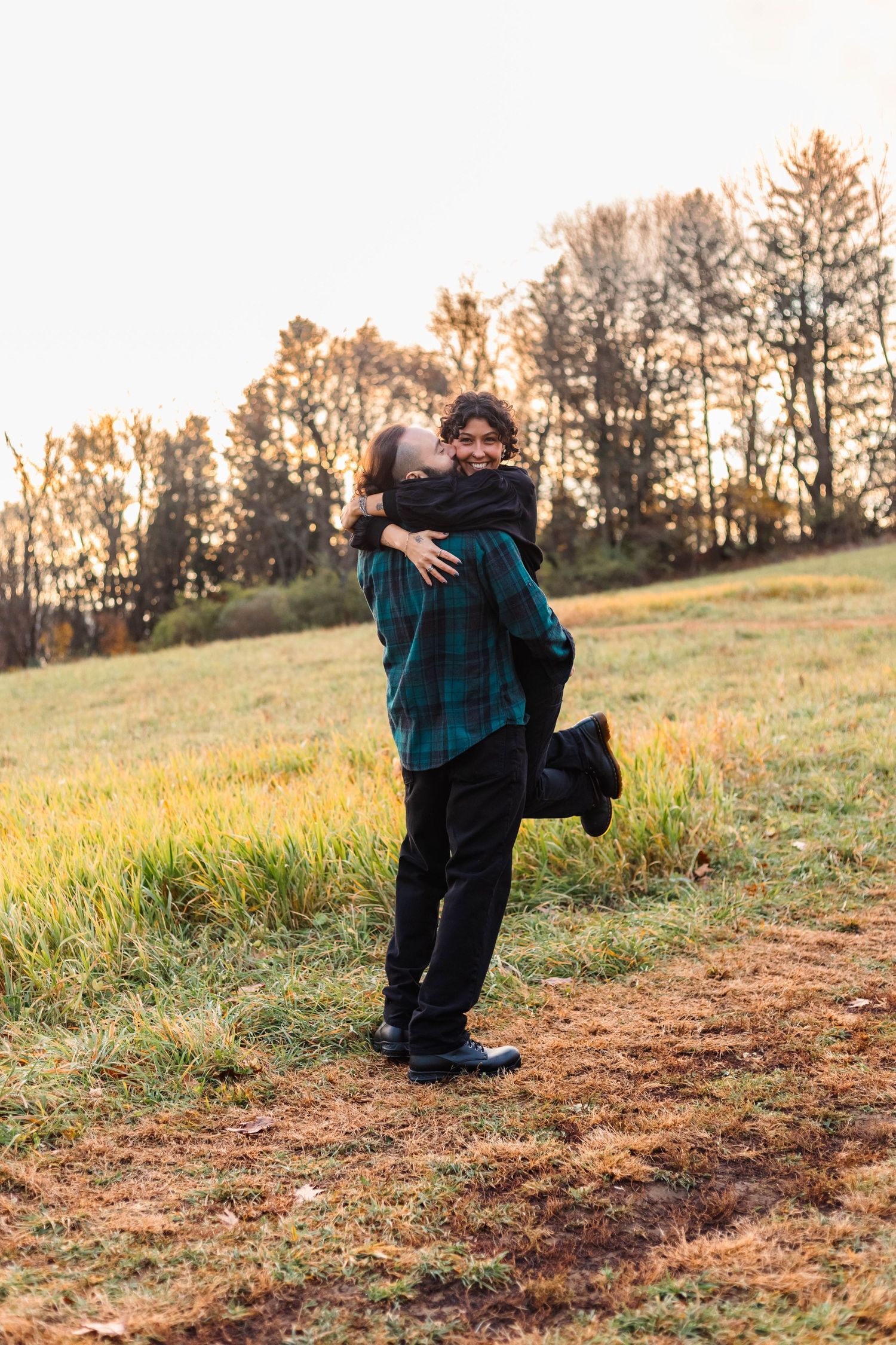 Couple sharing a joyful embrace in an autumn field at golden hour in West Chester, PA.