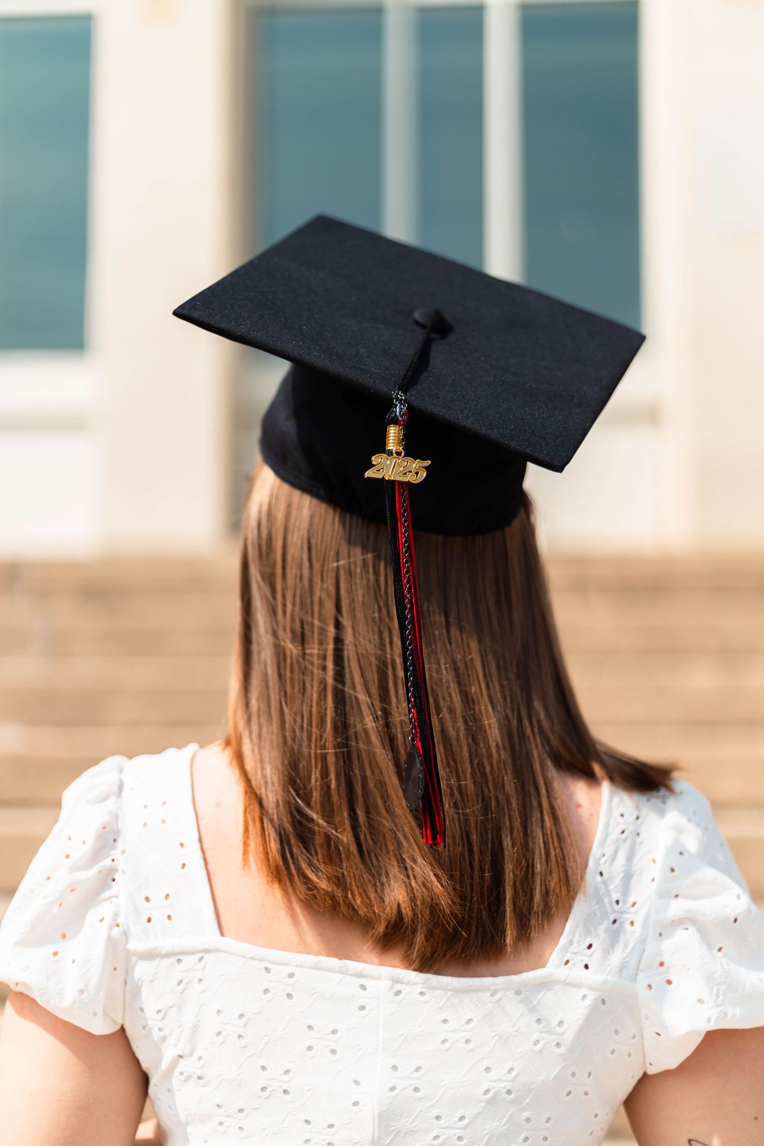 Back view of a Boyertown graduate wearing a black mortarboard cap with red and black tassel on graduation day.