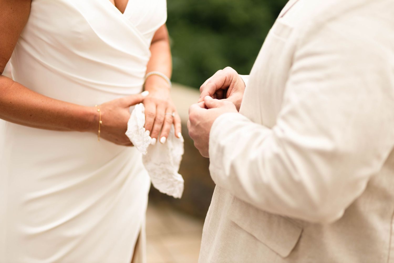 Groom placing a wedding ring on the bride's finger during an outdoor wedding ceremony.