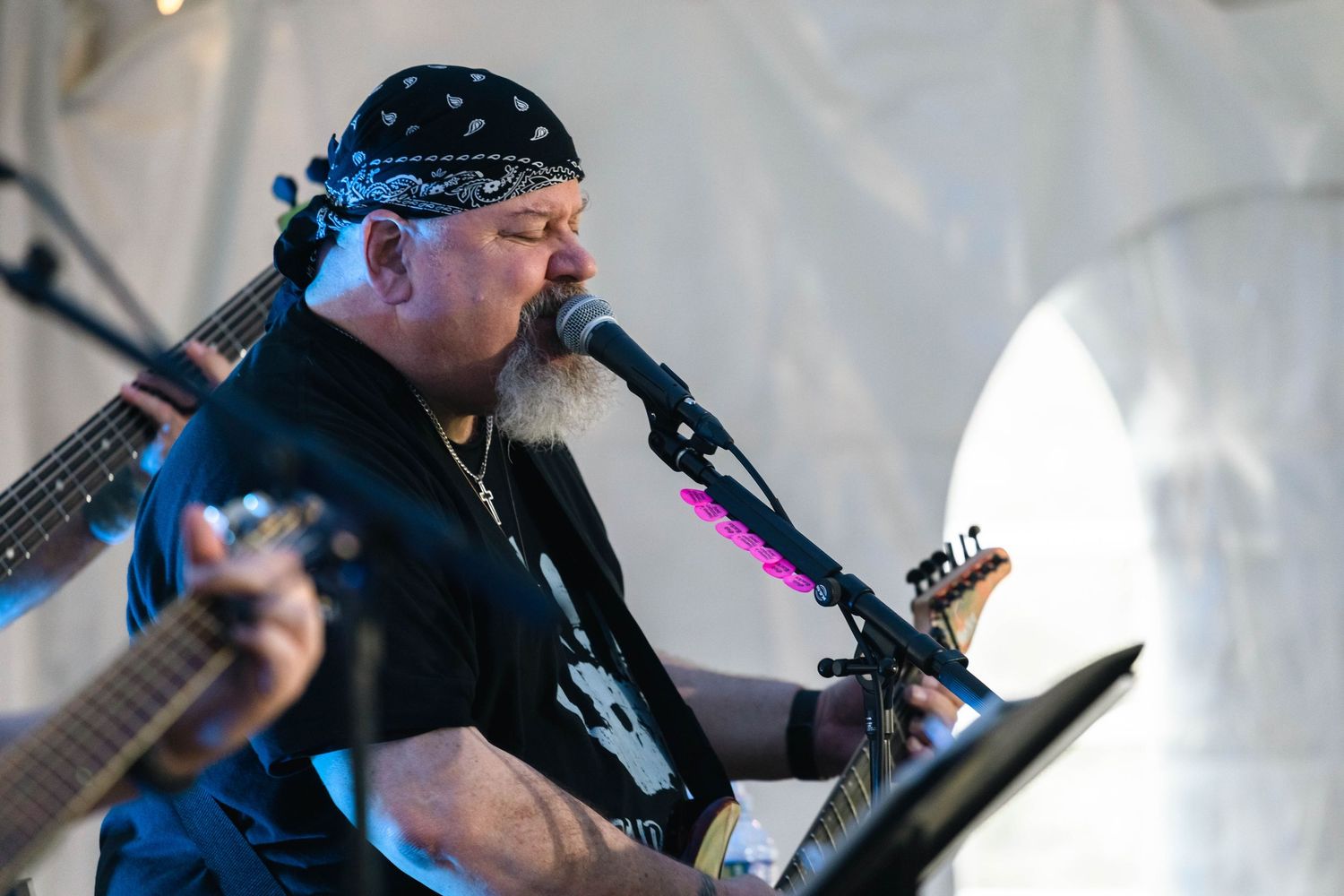 Bearded male guitarist in black bandana performing vocals on stage at an outdoor music event in Boyertown, PA.