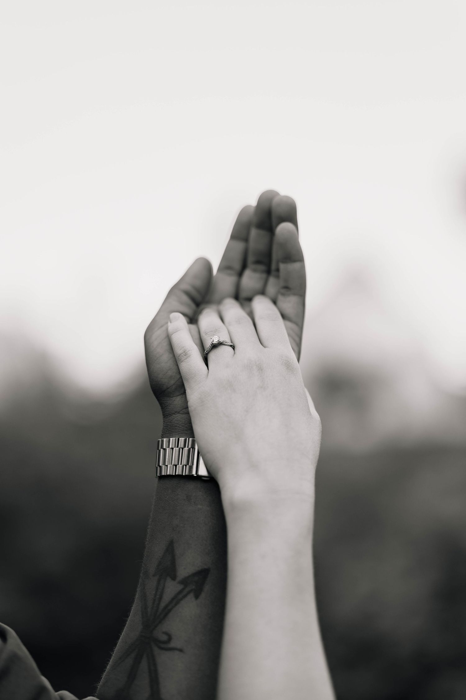 A black and white close-up of two hands raised together, one wearing an engagement ring and a watch at Grings Mill in Reading, PA.