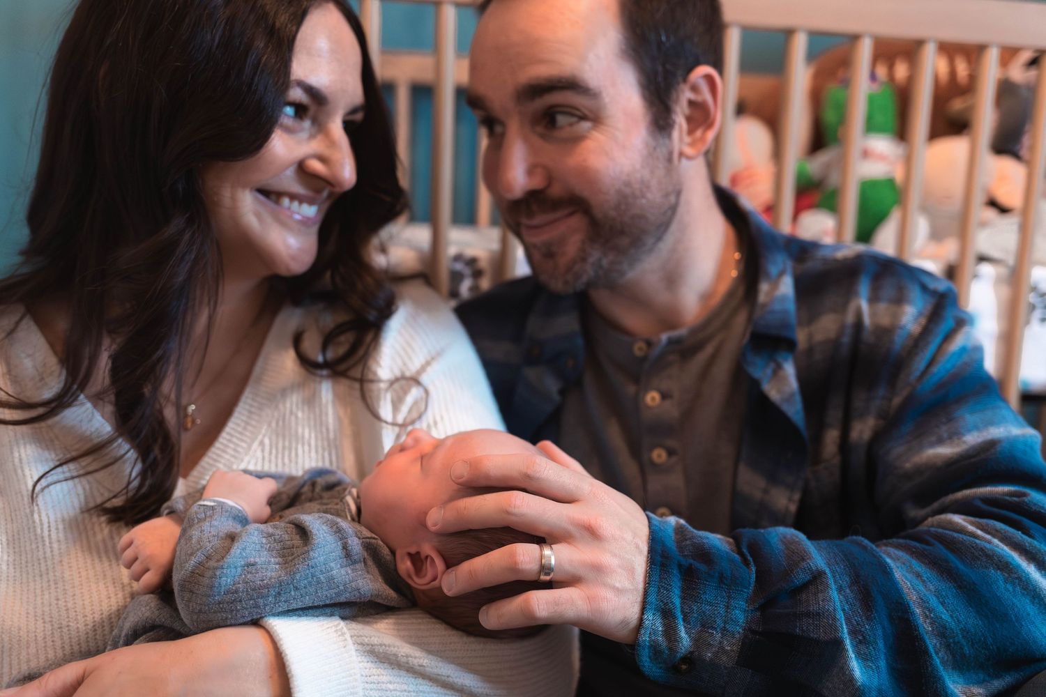 Adoring parents smiling at their newborn baby in a decorated nursery during a newborn session in Pottstown, PA.