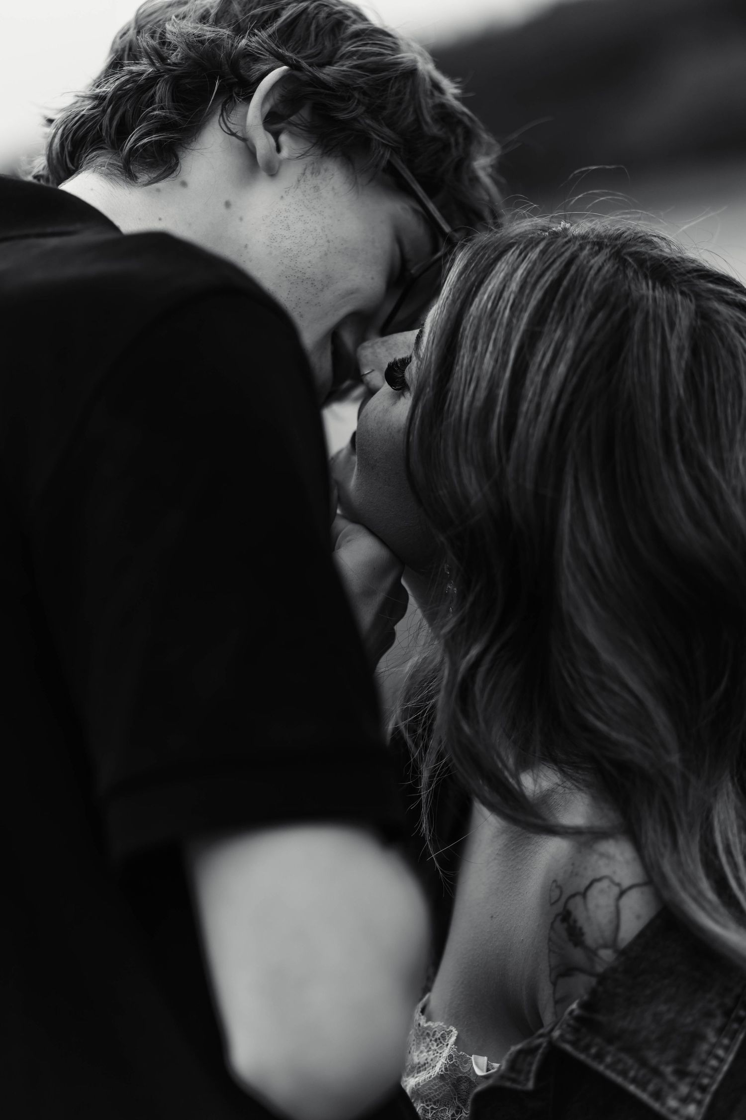 A black and white intimate close-up of a young couple sharing a tender kiss outdoors during an engagement session in Oley, PA.
