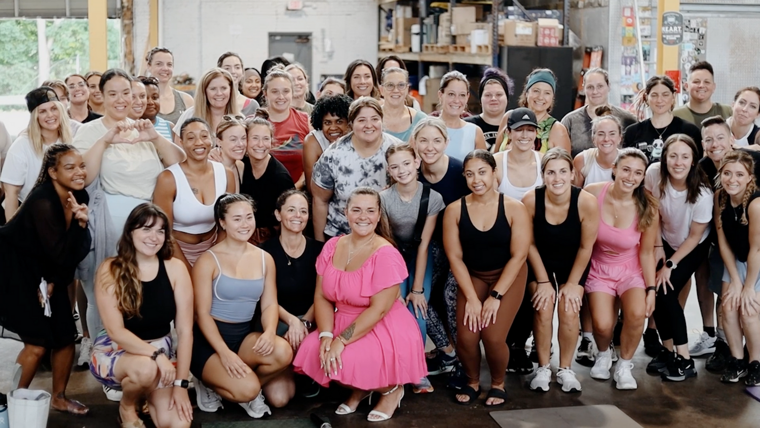 Large group of women of diverse backgrounds posing together for a photo inside a fitness studio.