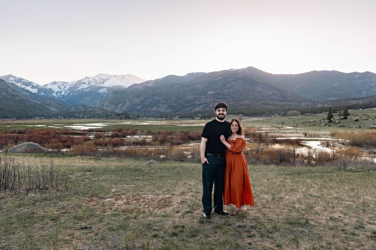 Couple poses together in a scenic mountain valley at sunset during their engagement session.