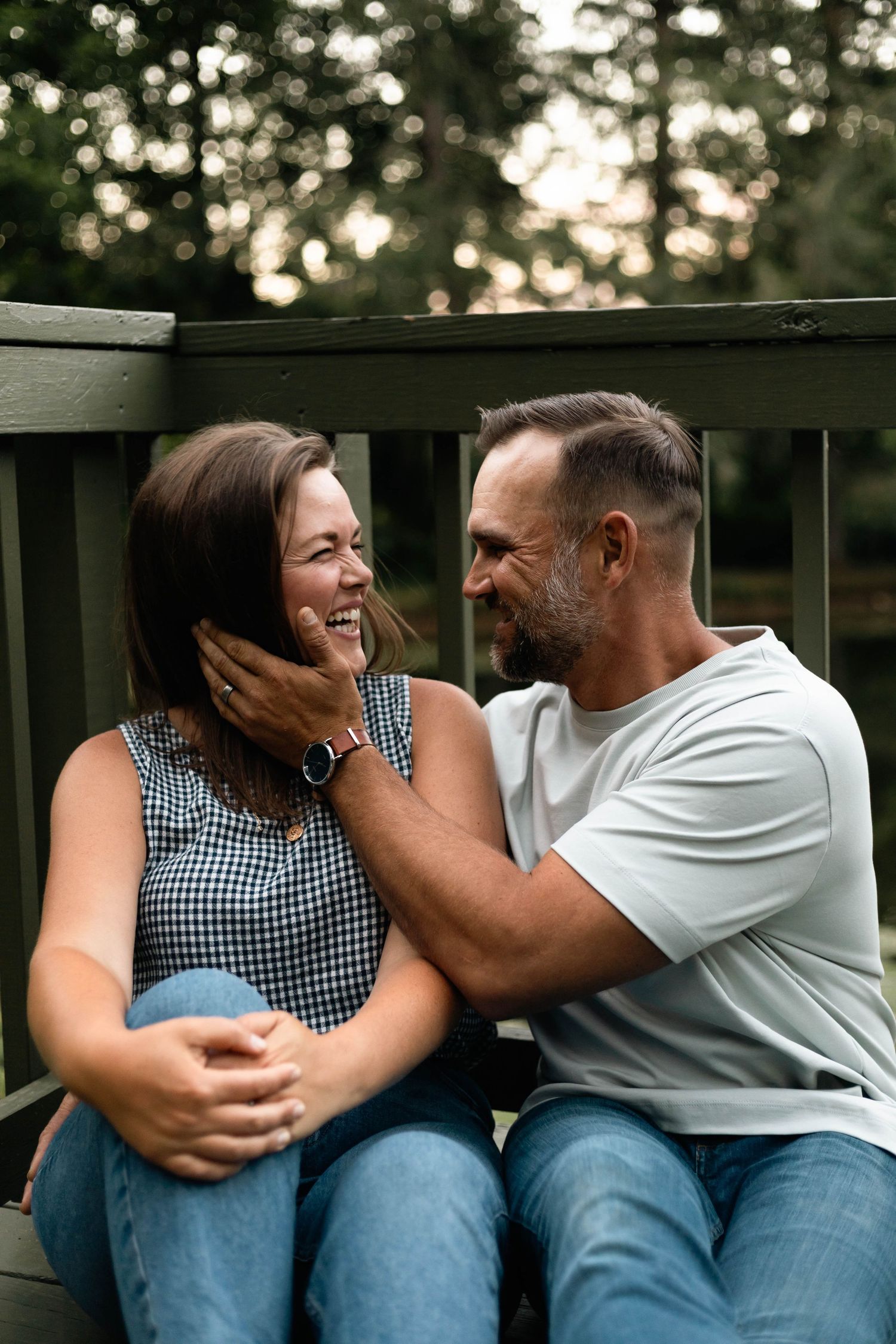 Affectionate couple sharing a tender moment on a deck, man gently cupping womans face as she laughs in Boyertown, PA.