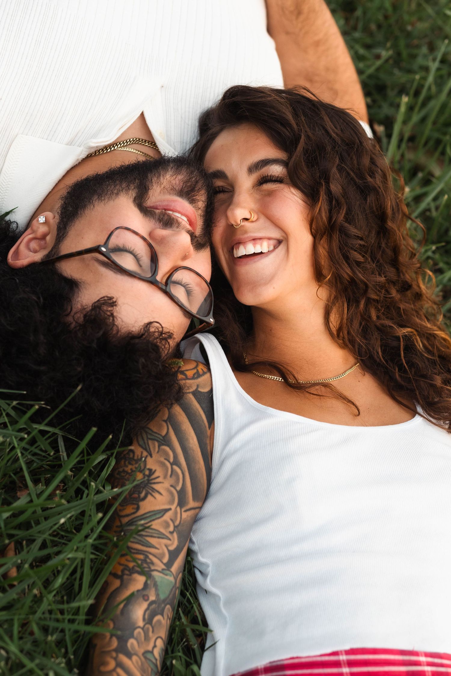 Joyful couple lying in grass laughing together during an engagement session in Elverson, PA.